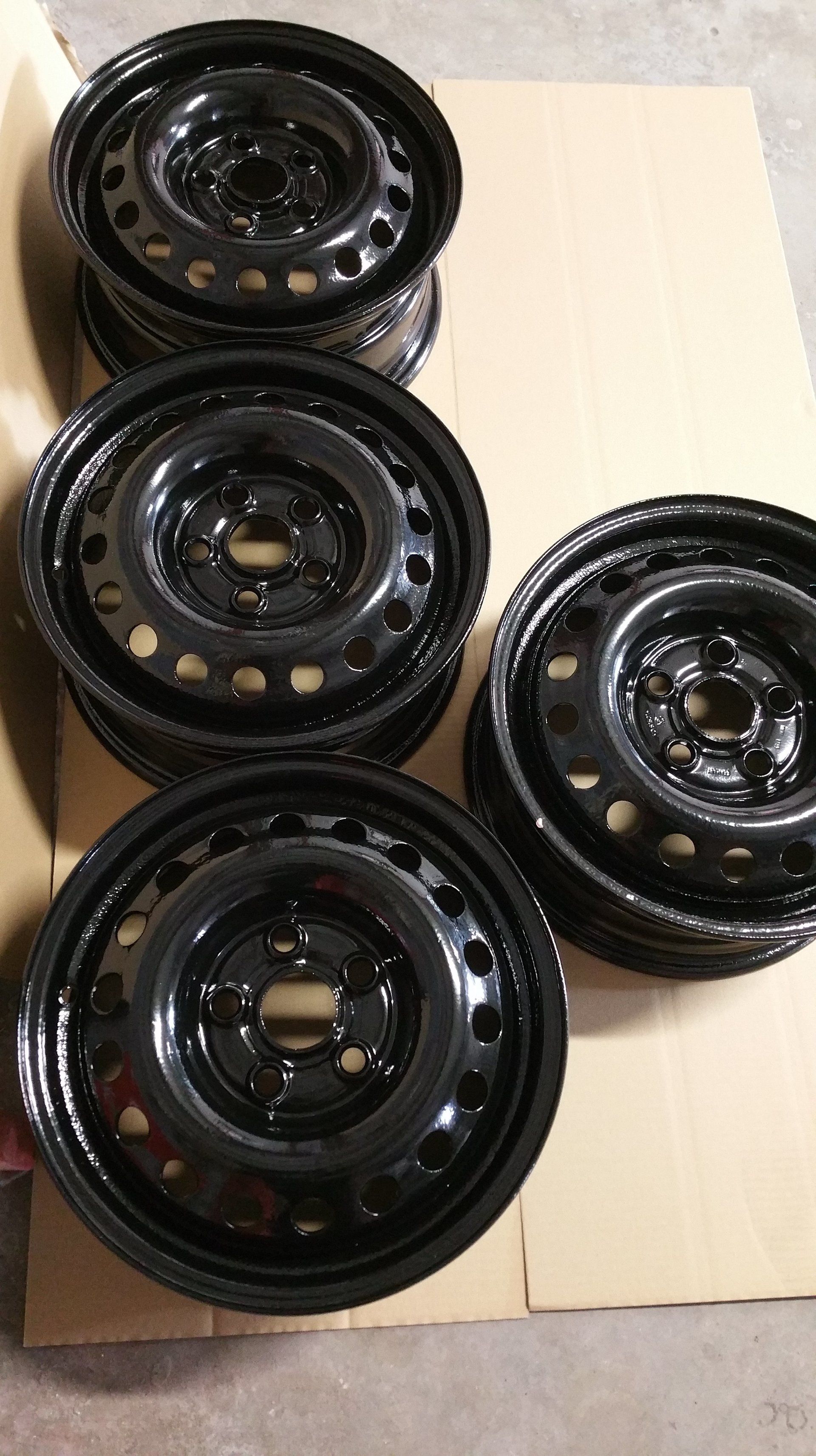 A stack of black rims sitting on top of each other on a cardboard box.