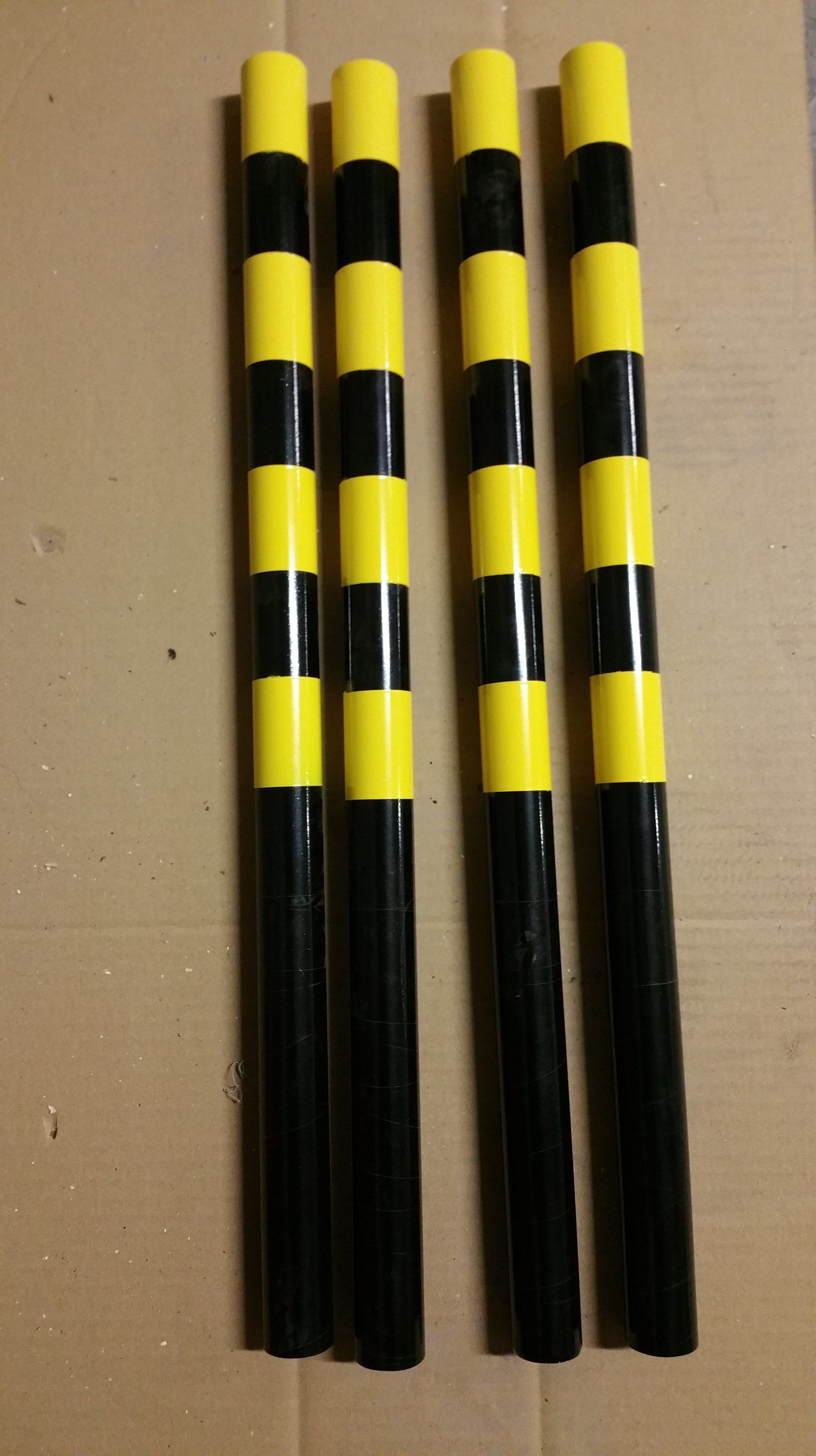Three yellow and black striped poles are sitting on a cardboard box
