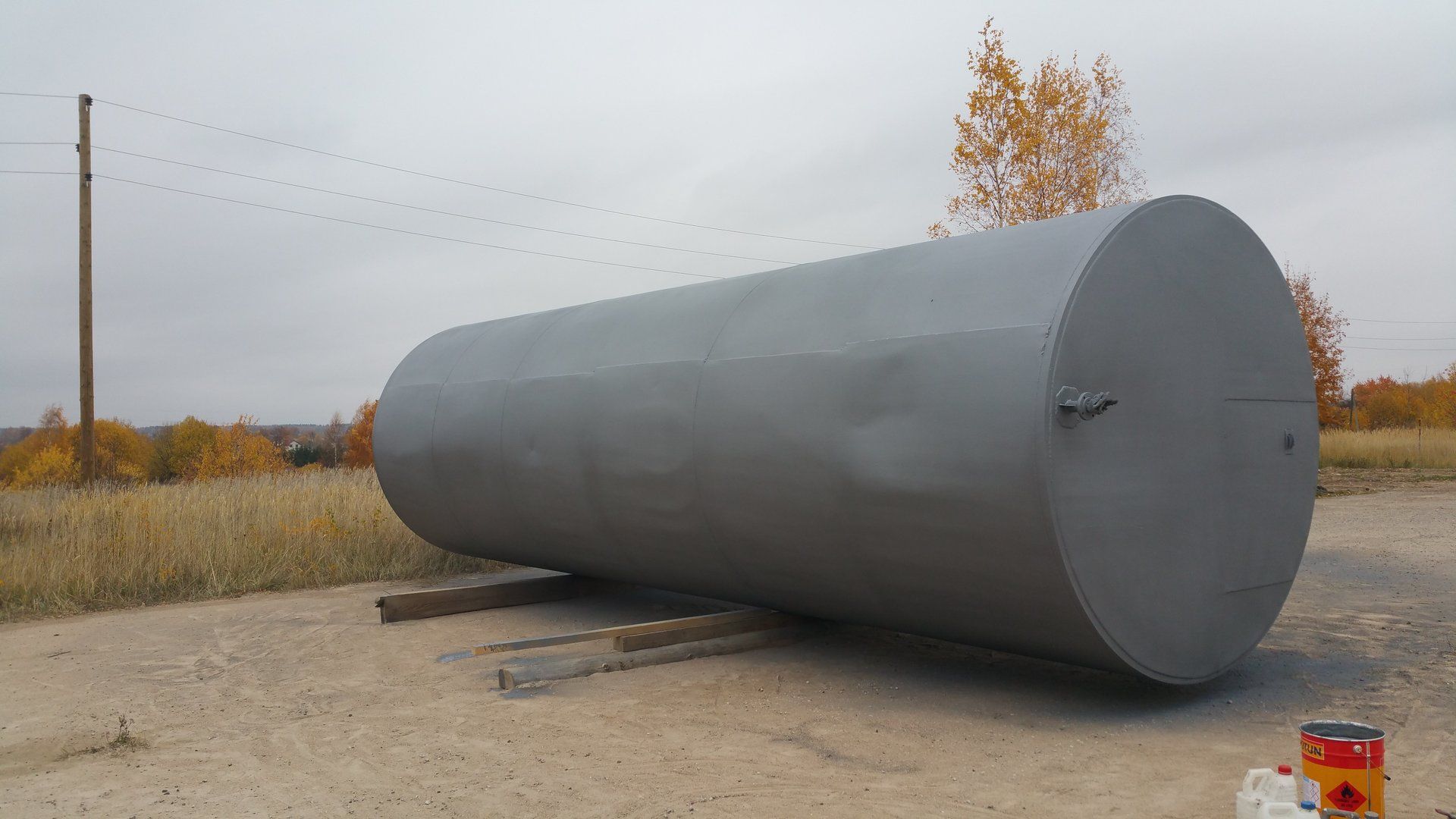A large metal tank is sitting on top of a dirt road.