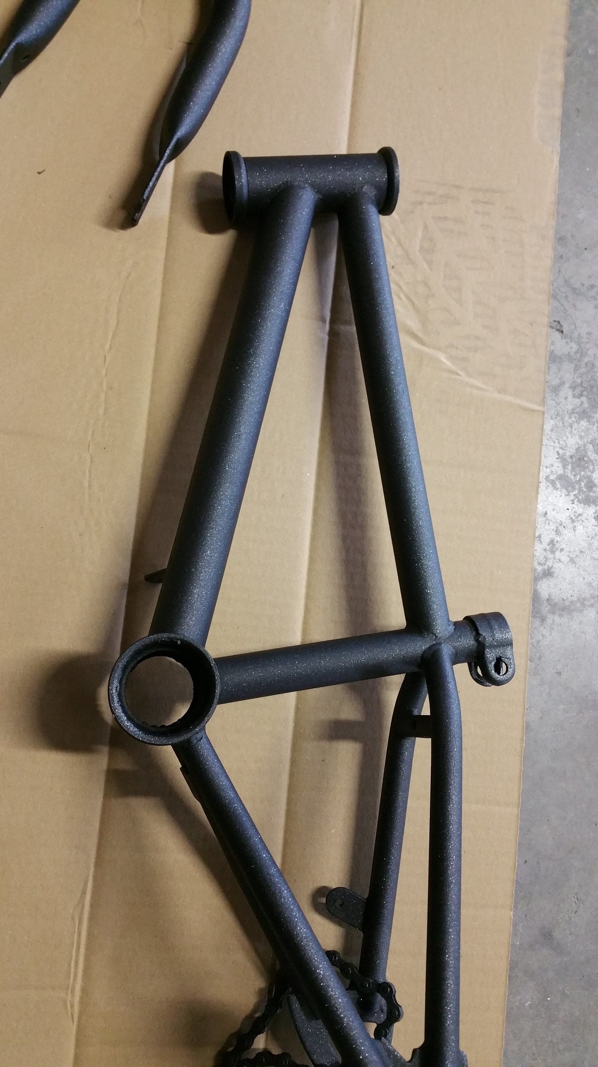 A bicycle frame is sitting on top of a cardboard box.