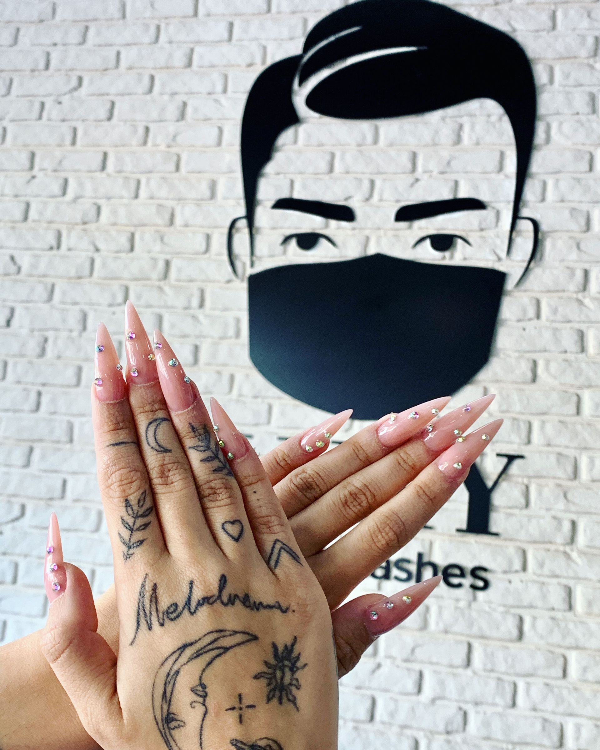 Eine Frau mit langen Nägeln und einem Tattoo auf der Hand