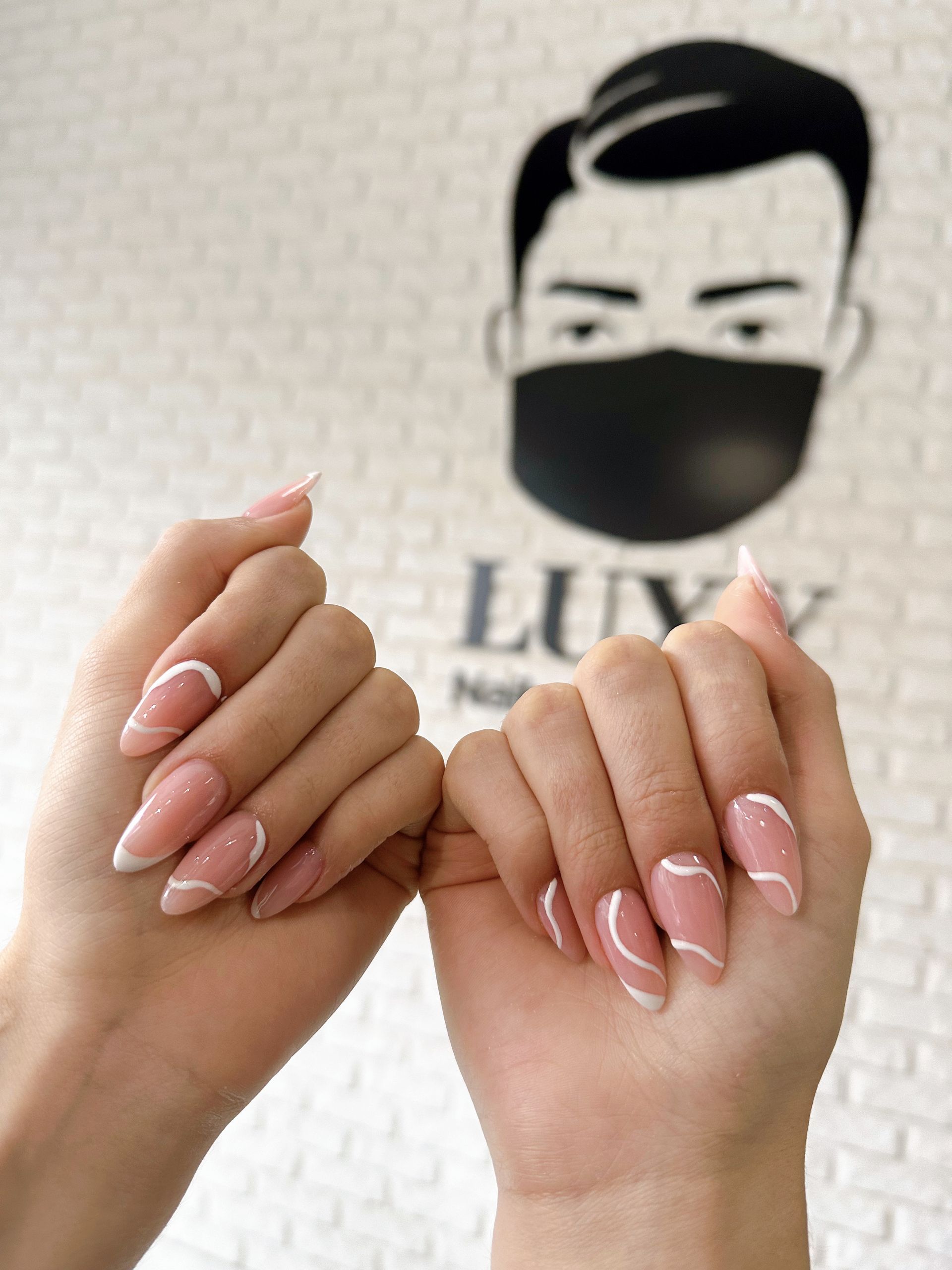 eine Frau hält ihre Nägel in einem Nagelstudio in der Nähe eines Mannes mit Maske .