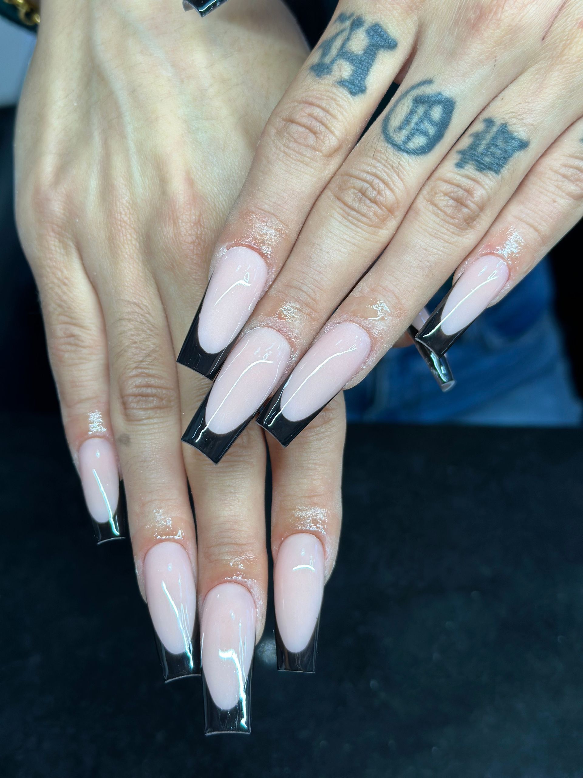 Eine Nahaufnahme der Nägel einer Frau mit einem Tattoo auf ihrem Finger