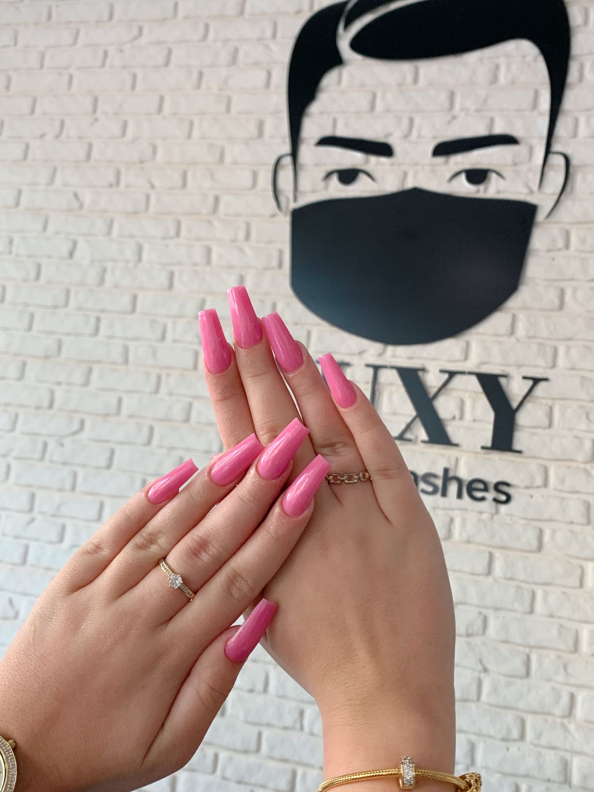 Die Hände einer Frau mit rosa Nägeln vor einem Schild mit der Aufschrift „Voxy“