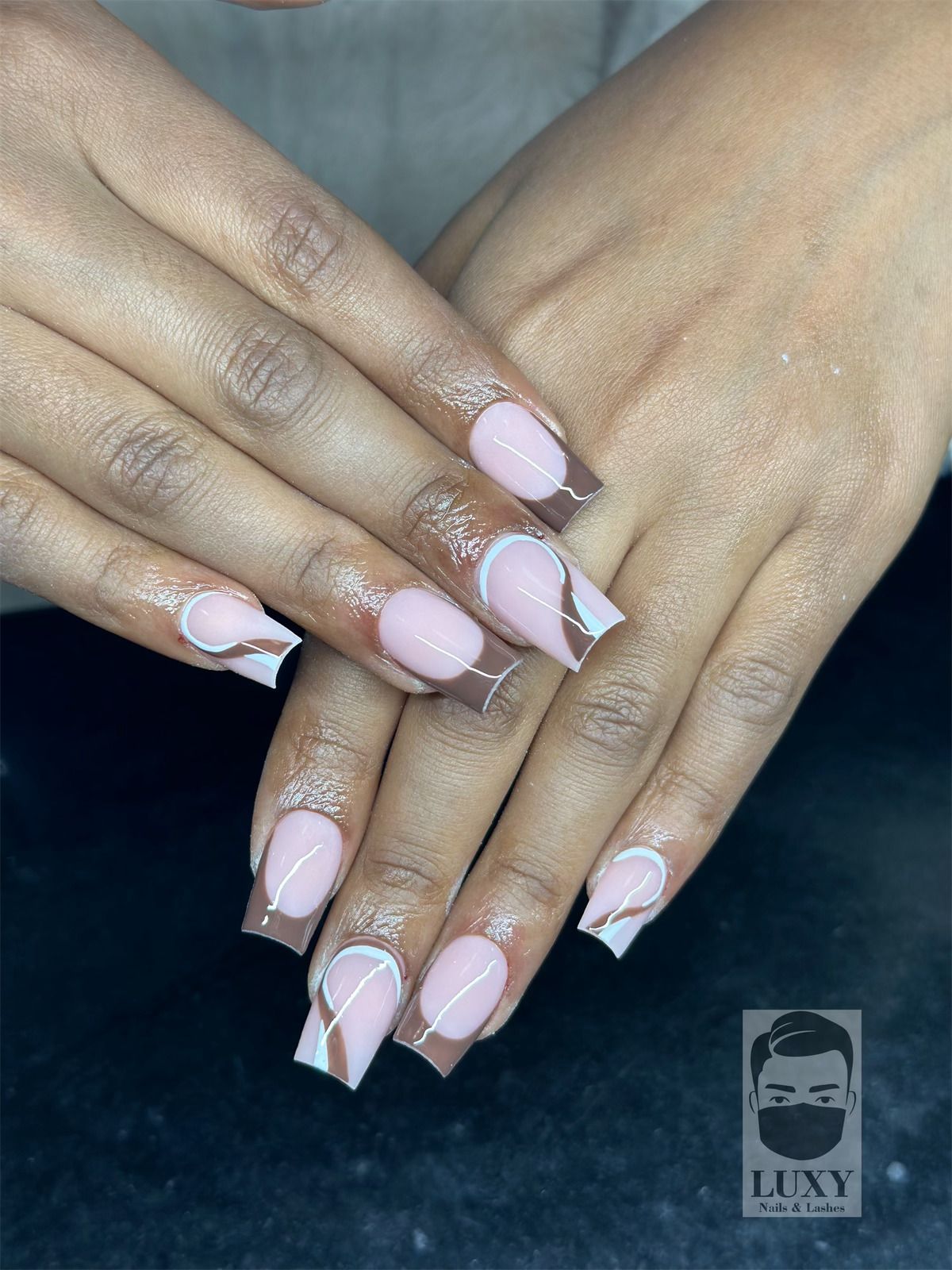 Eine Nahaufnahme der Hände einer Frau mit rosa und weißen Nägeln.