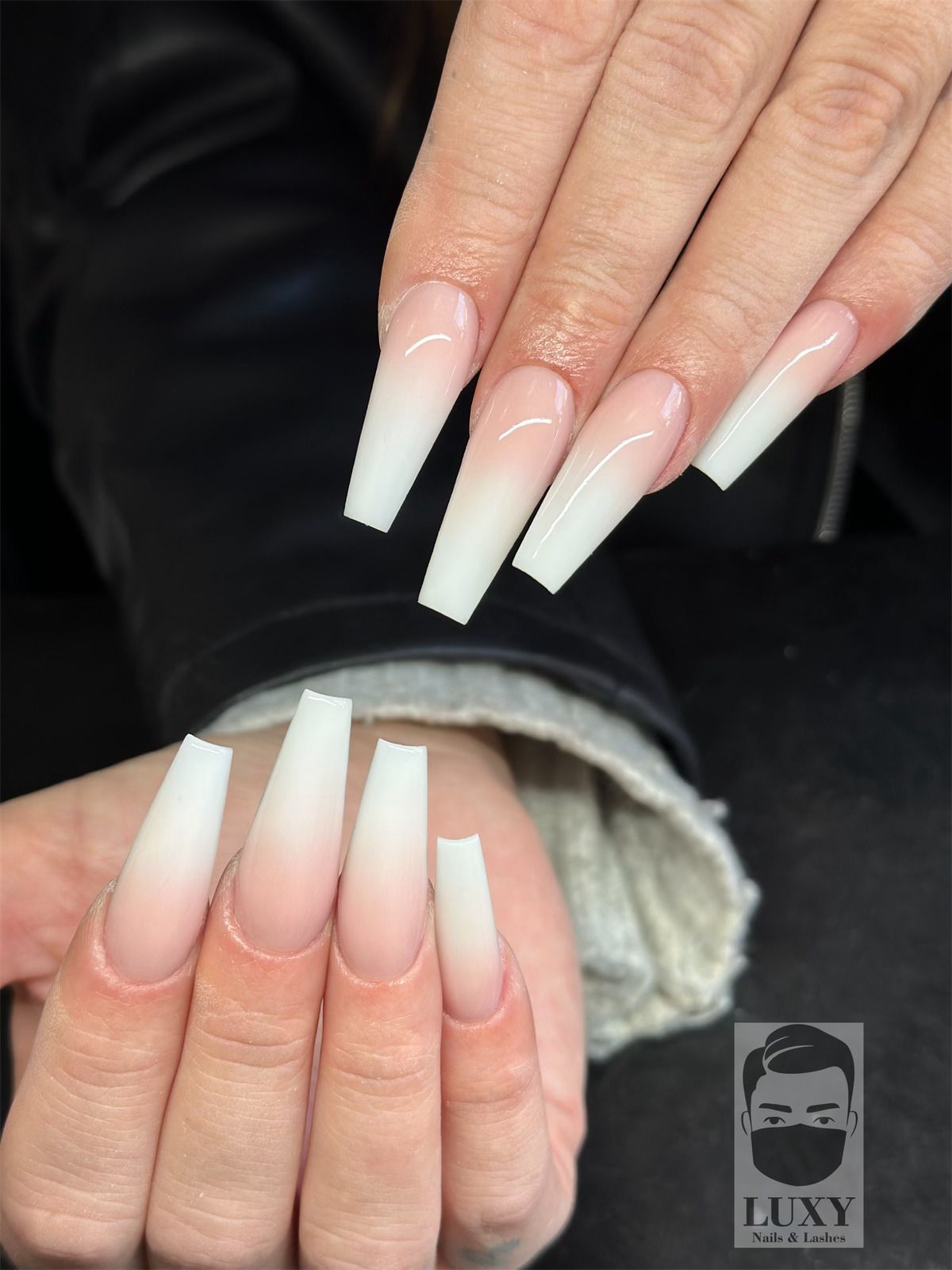 Eine Nahaufnahme der Nägel einer Person mit einem Luxy-Logo in der Ecke