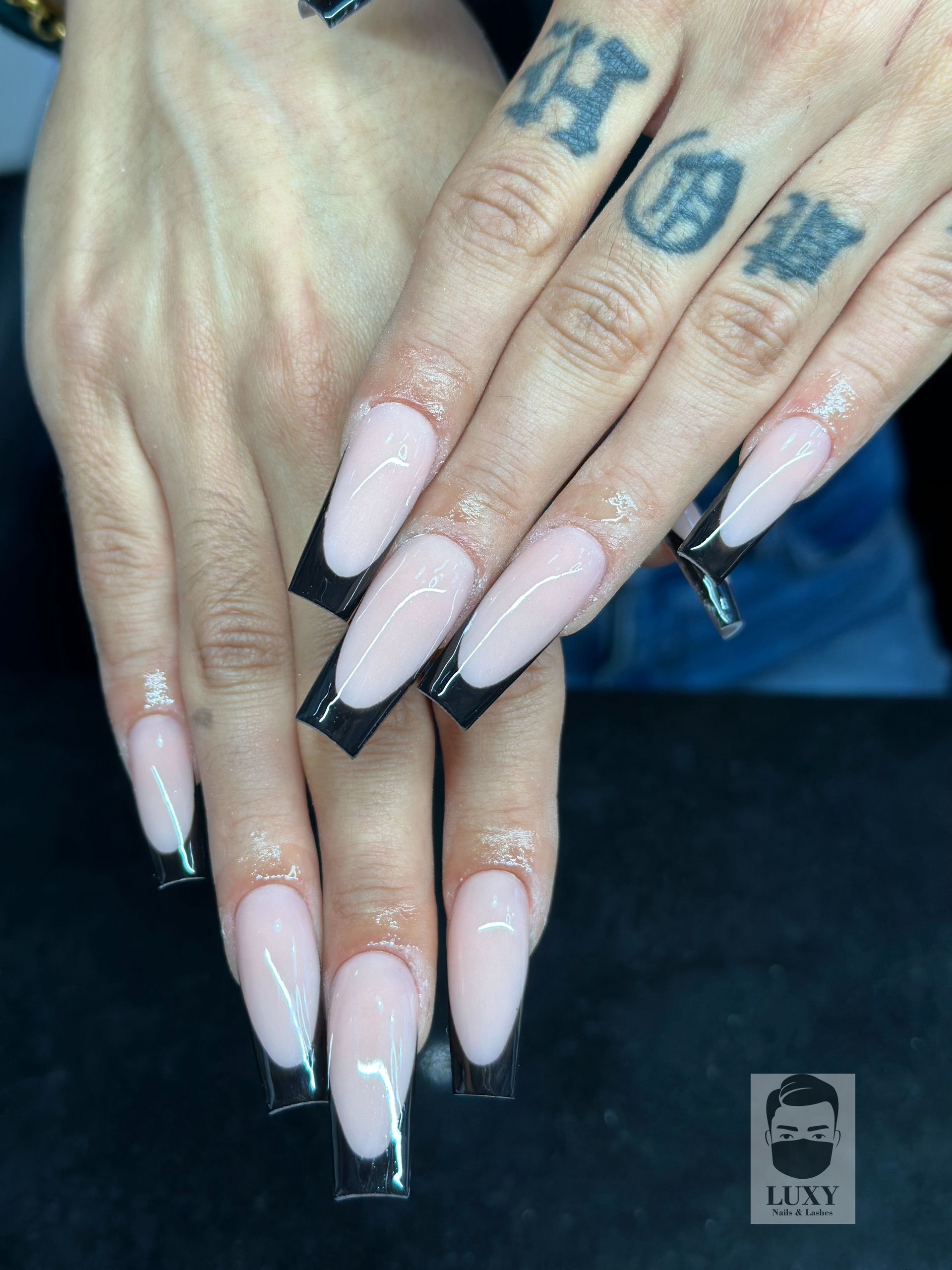 Eine Nahaufnahme der Nägel einer Frau mit einer schwarzen French Manicure