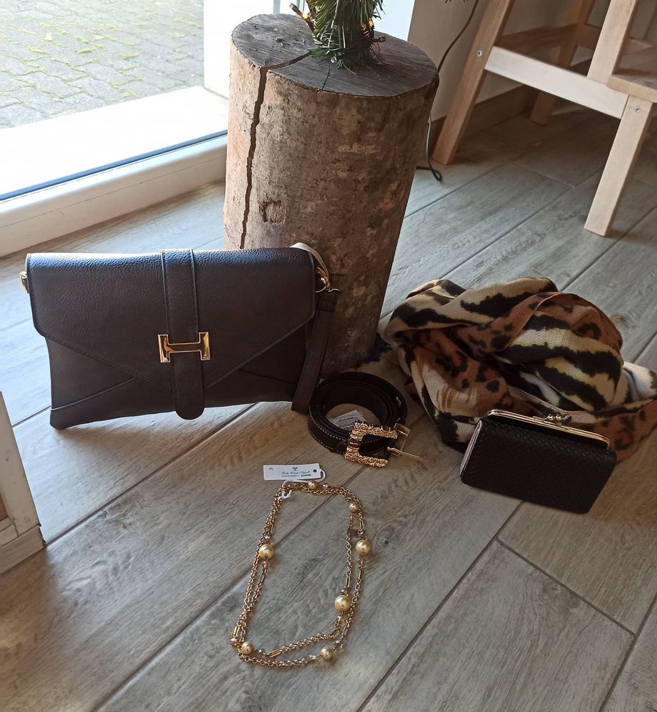Una borsa e una collana sono su un pavimento di legno accanto a un ceppo d'albero.