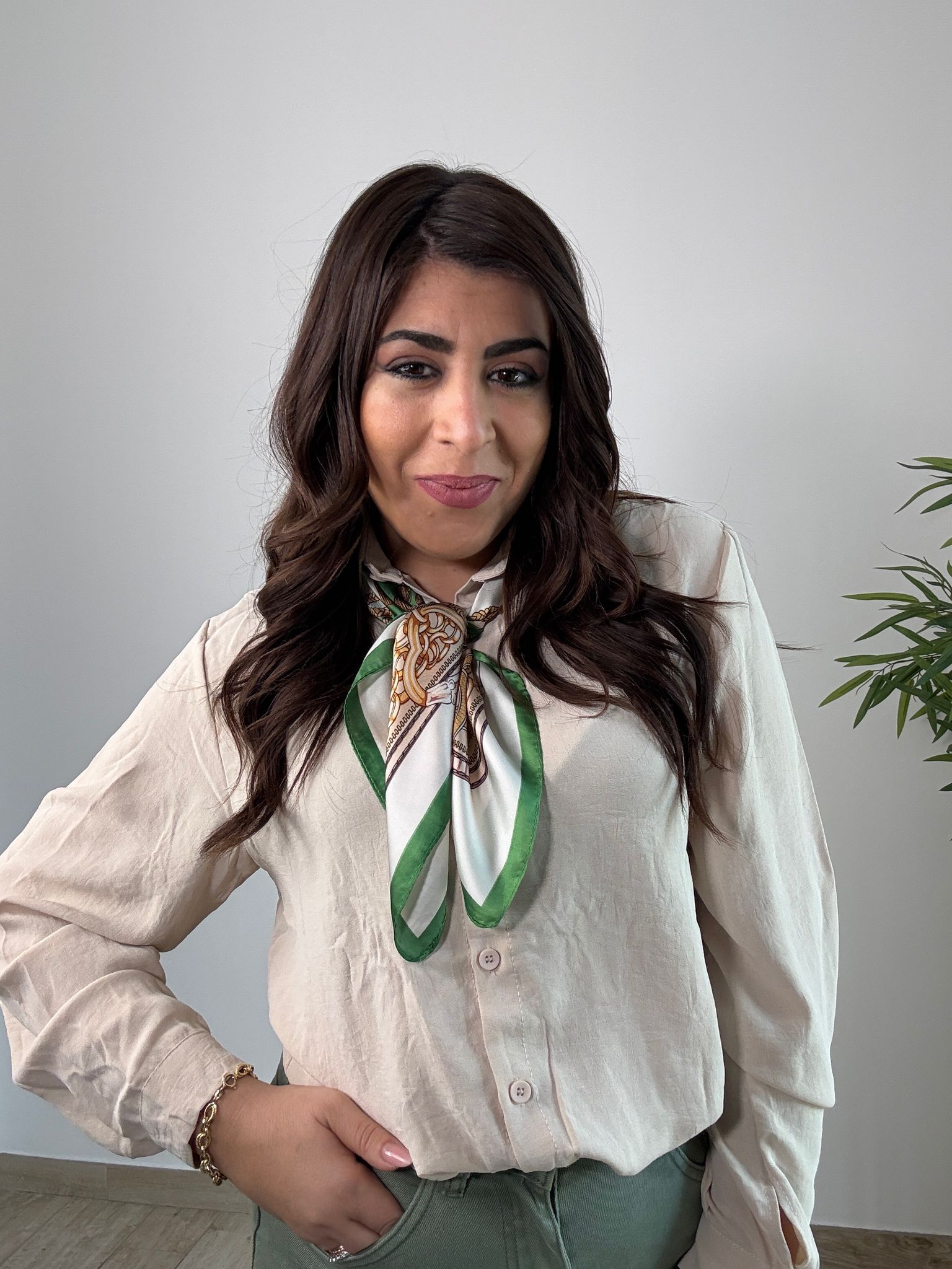 Una donna che indossa una camicia bianca e una sciarpa verde intorno al collo.
