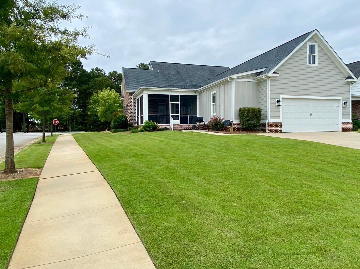 A house with a screened in porch and a lush green lawn