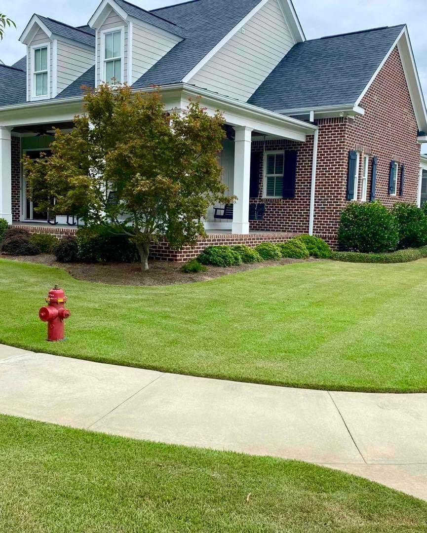A large brick house with a red fire hydrant in front of it.