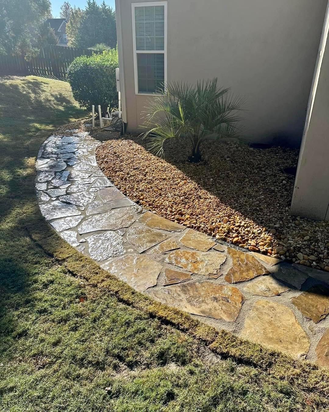 A stone walkway leading to a house in a backyard.