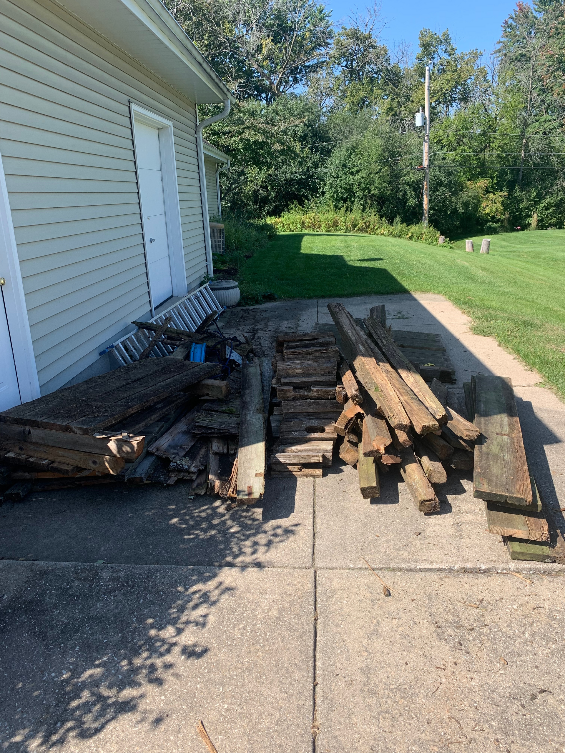 a pile of wood is sitting on the sidewalk in front of a house .