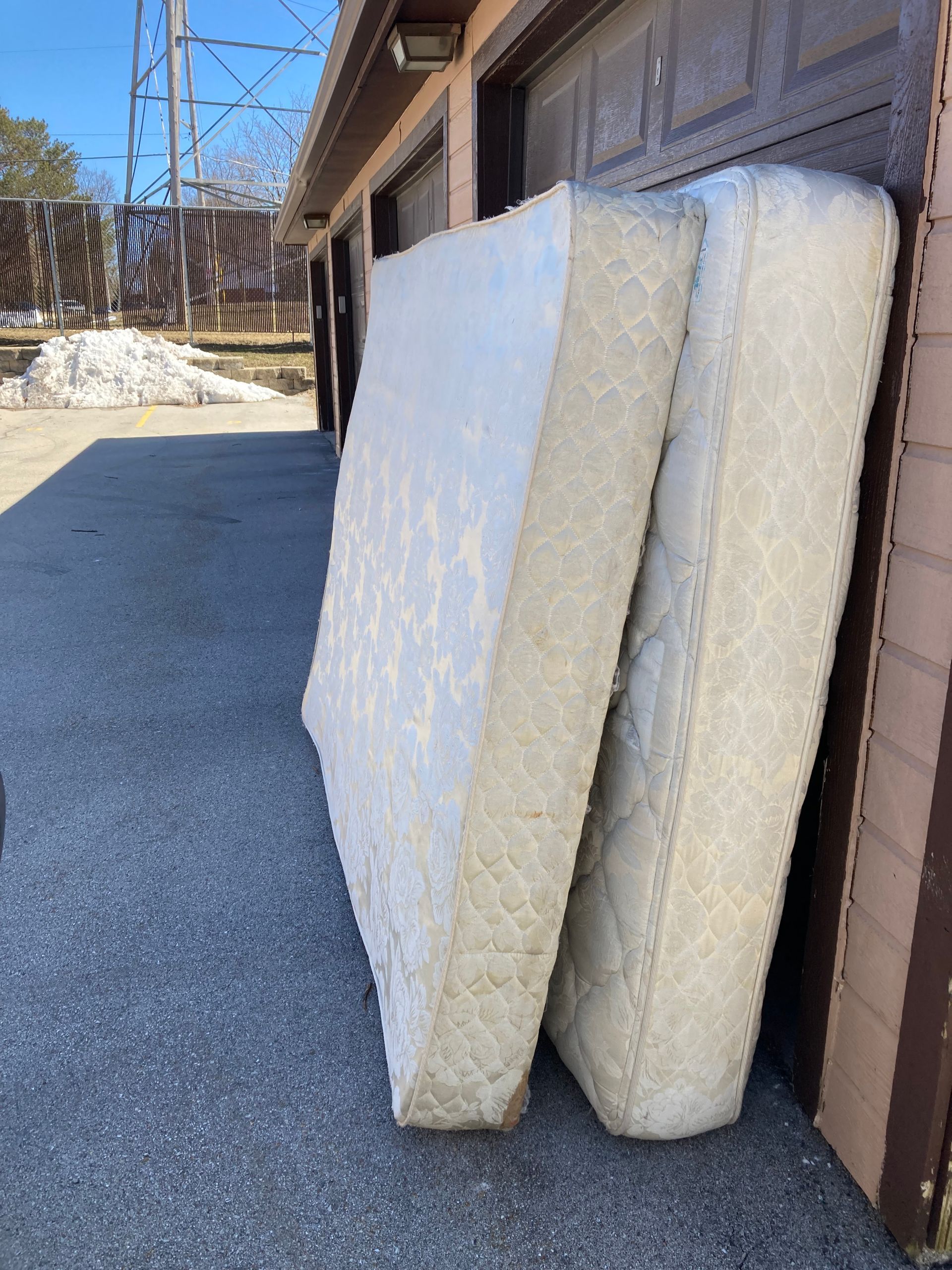 two mattresses are stacked on top of each other in front of a garage door