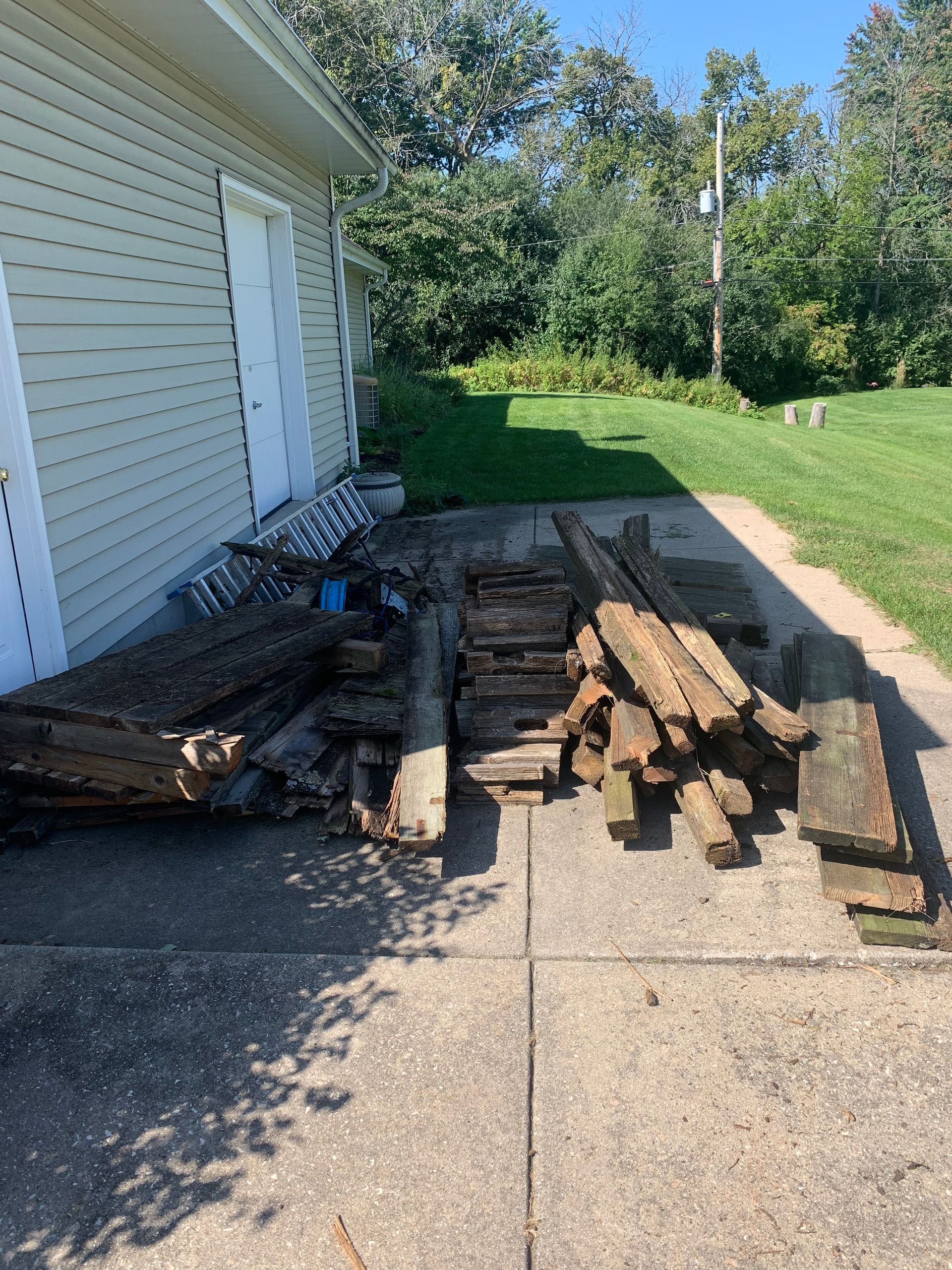 a pile of old, used wood sitting on the sidewalk in front of a house .