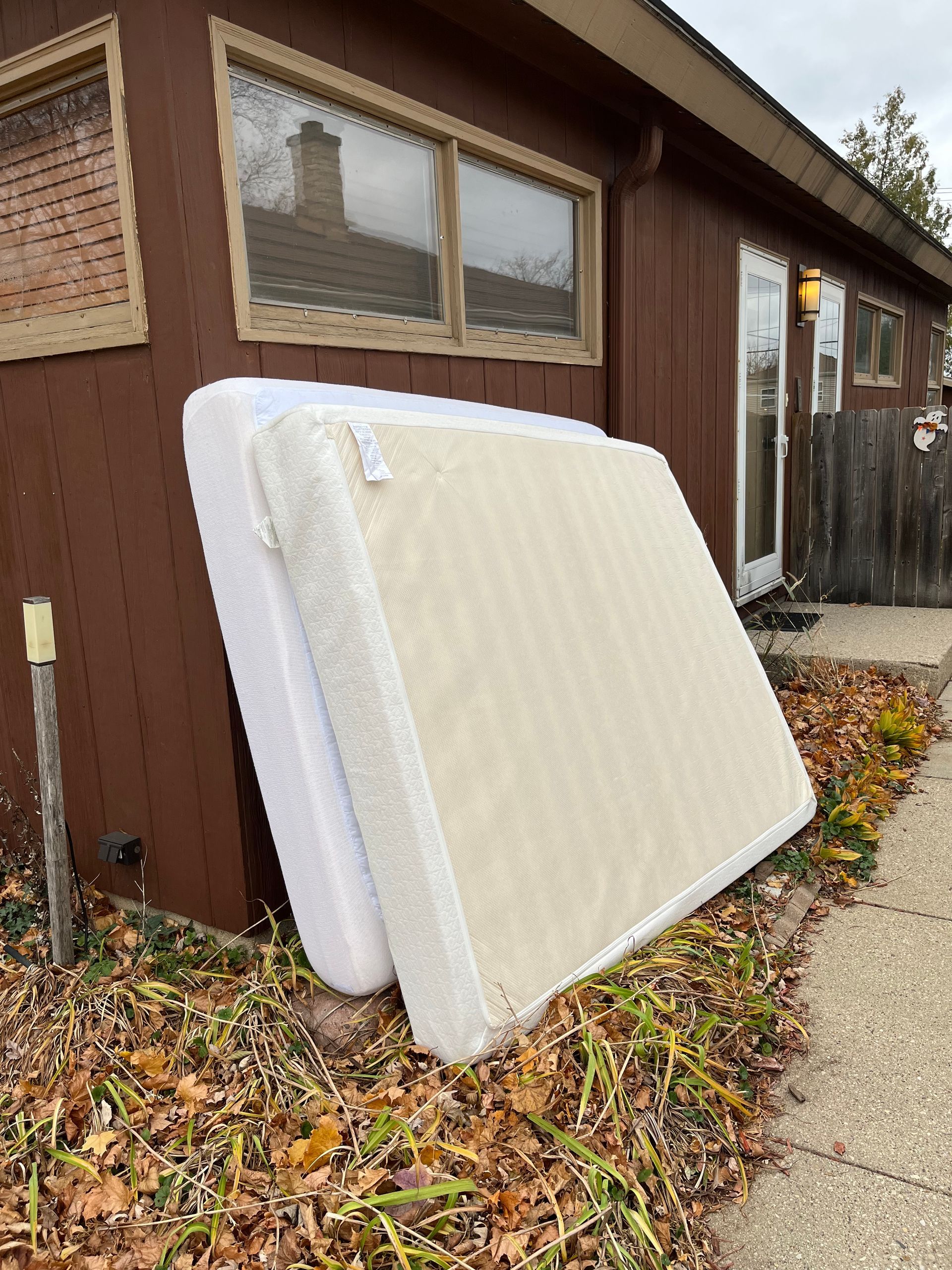 two mattresses are stacked on top of each other in front of a house .