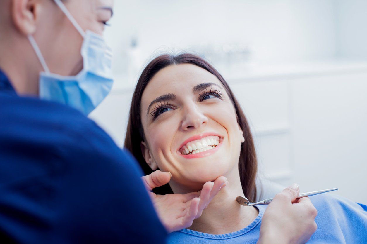 A woman is smiling while having her teeth examined by a dentist.