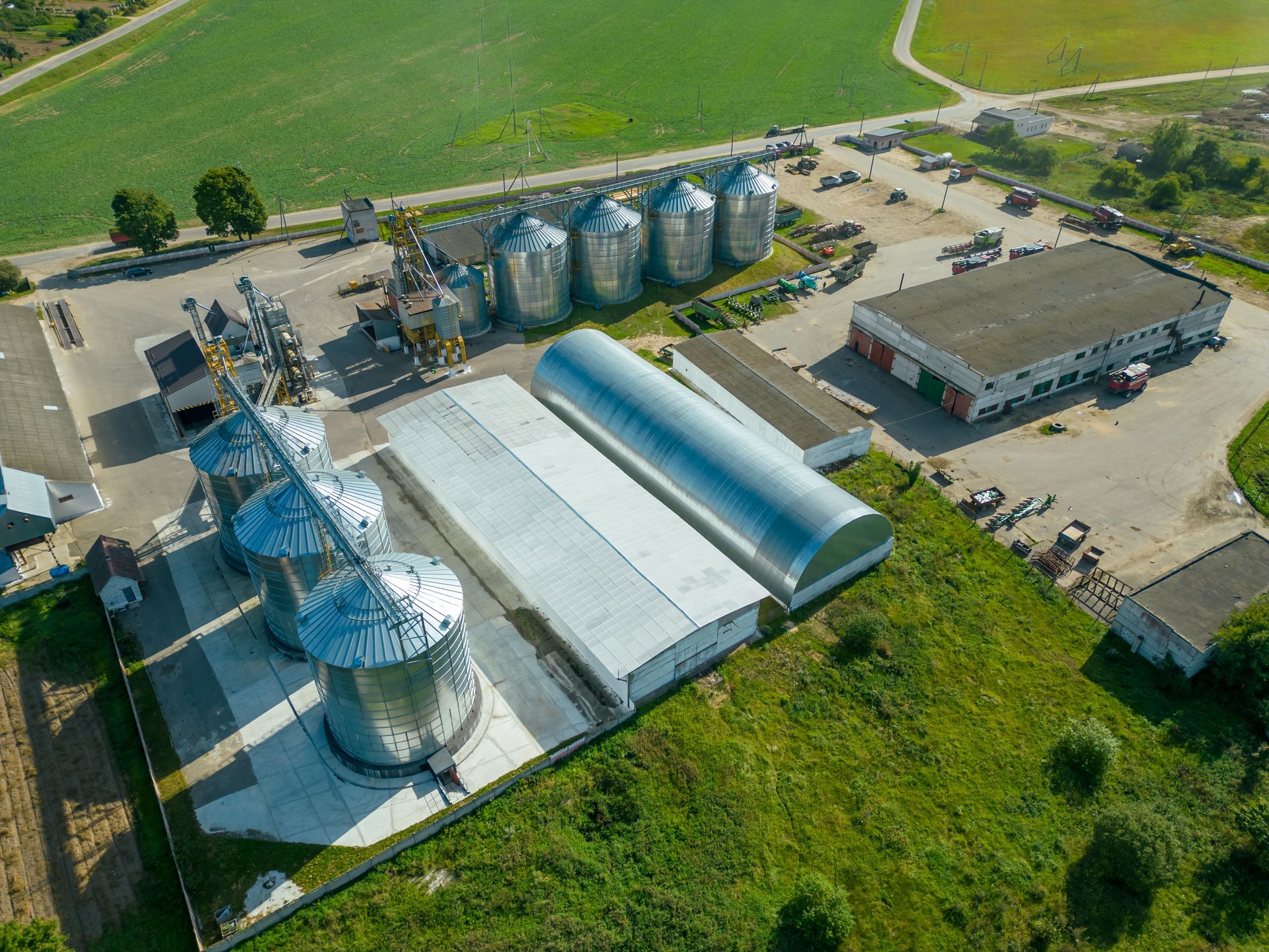 Aerial view of an agricultural complex with silos, storage buildings, and a surrounding field.