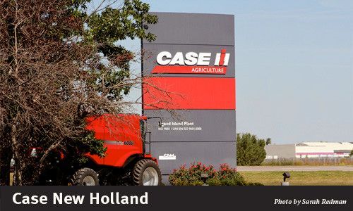 Sign for Case New Holland Agriculture, red and gray, with a red tractor nearby.