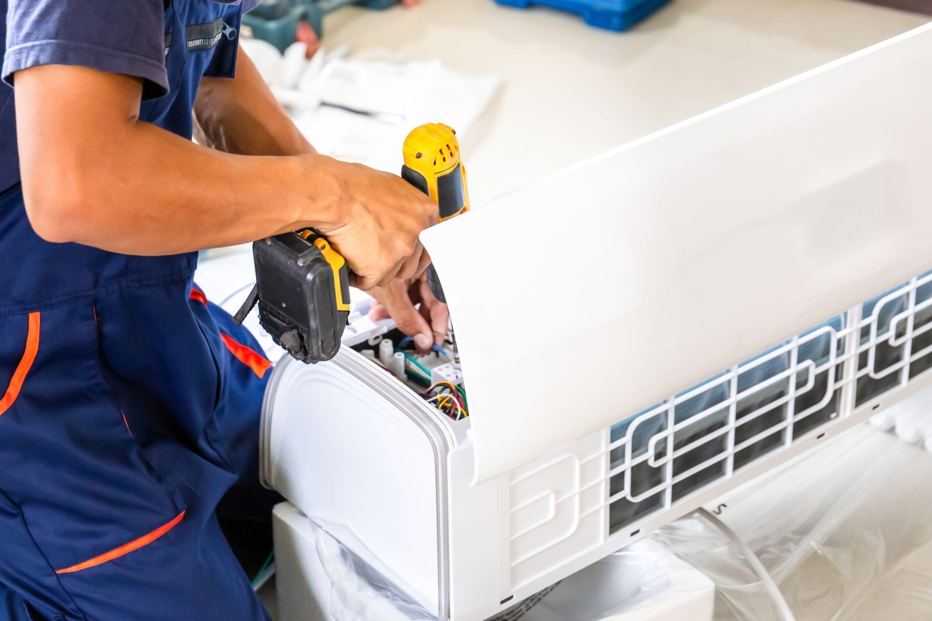 Technician repairing a white air conditioner unit with tools