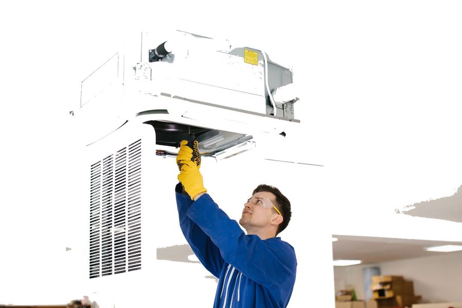 Technician inspecting a ceiling-mounted HVAC unit in a bright room