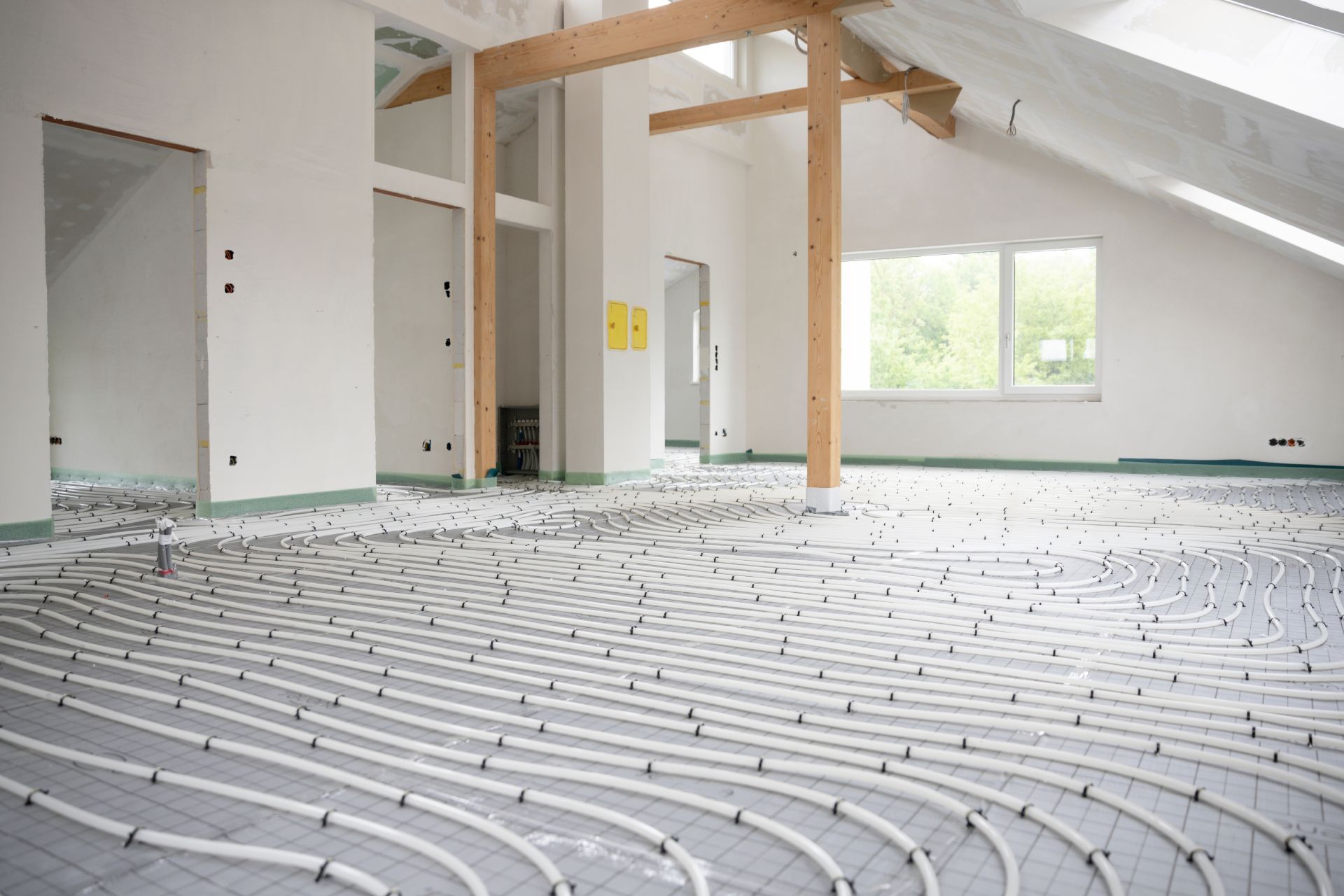 Empty room with white underfloor heating pipes installed and windows on the right