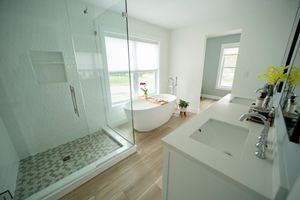 Modern bathroom with a glass shower, soaking tub, double vanity, and window.