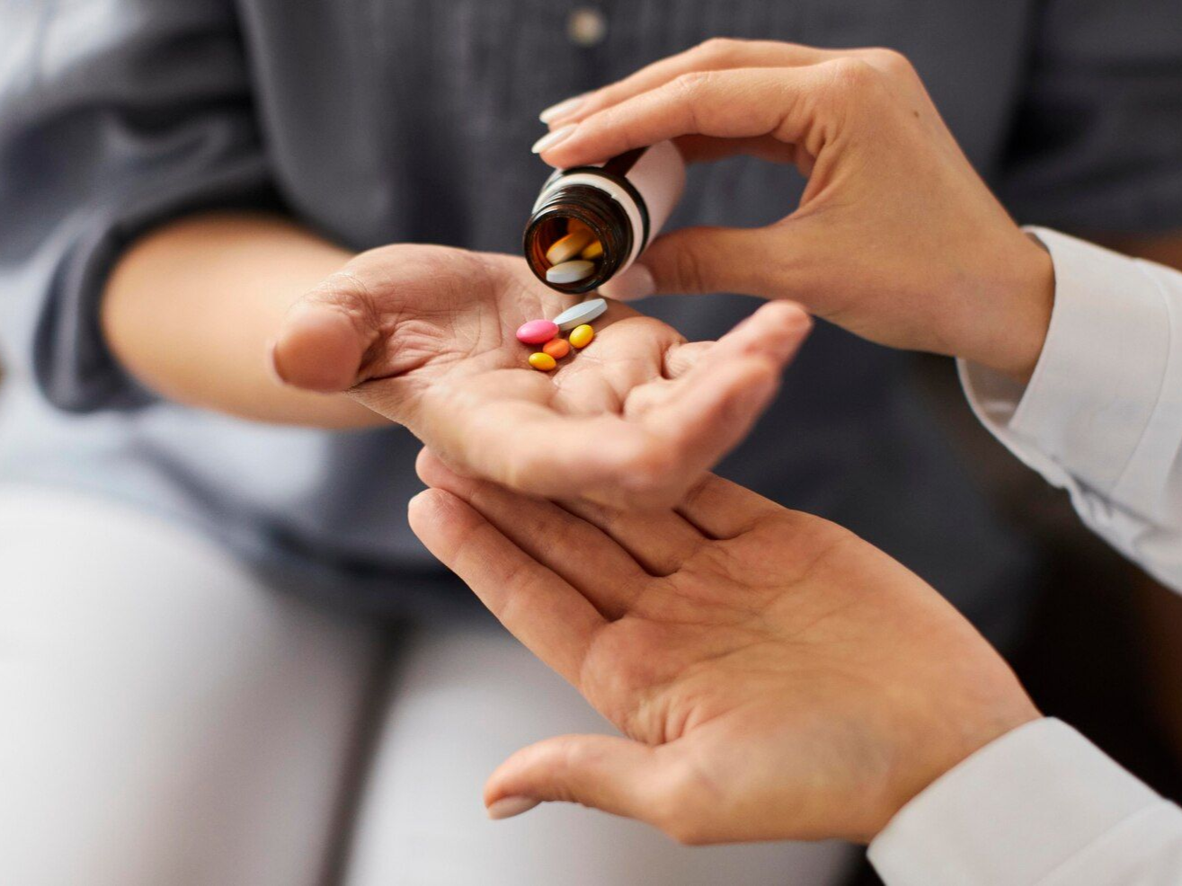 Hands pouring pills from a bottle into another hand.