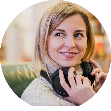 Woman holding headphones, smiling, in a bright interior.