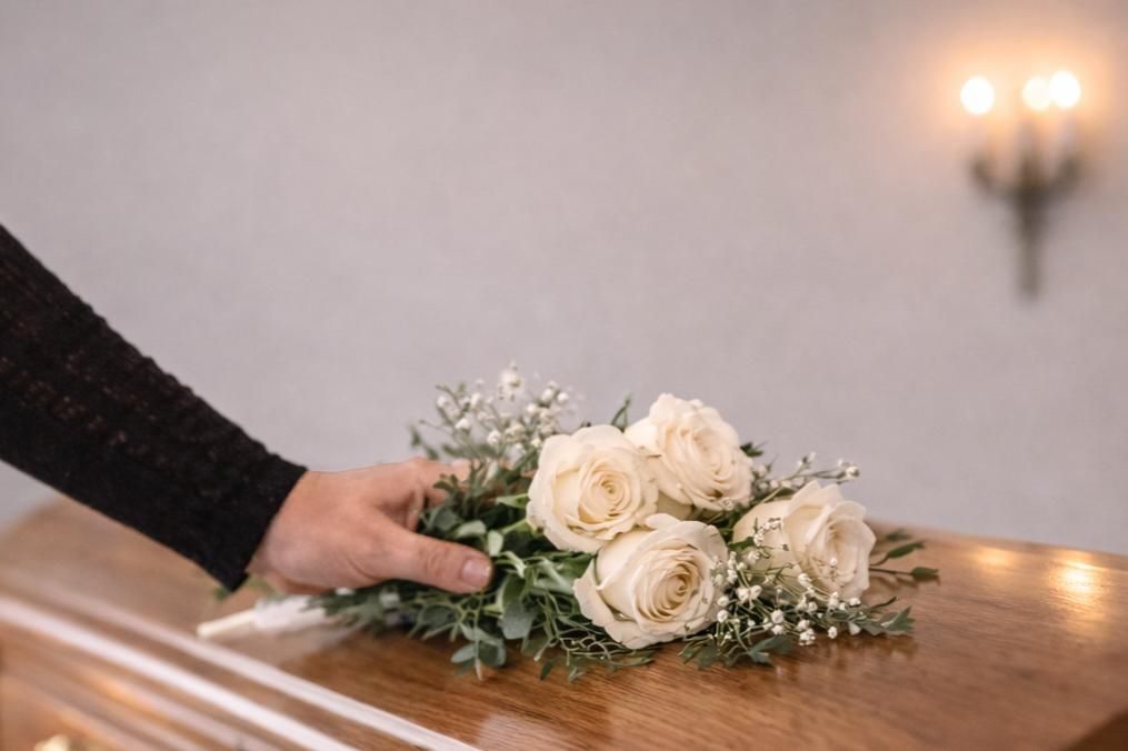 Elegant memorial display featuring a bronze urn surrounded by white and blush floral arrangements and lit candles, reflecting compassionate services offered by a Delta, PA funeral home and cremations provider.