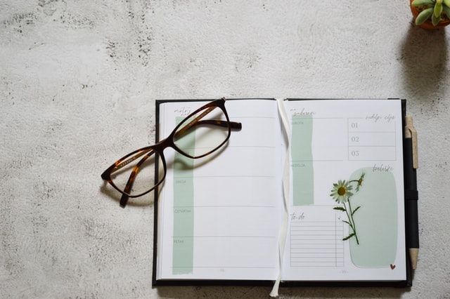 Open planner with glasses and pen on a table, symbolizing organization and thoughtful planning, often used by funeral homes in Delta, PA to guide families through funeral arrangements and memorial service details.