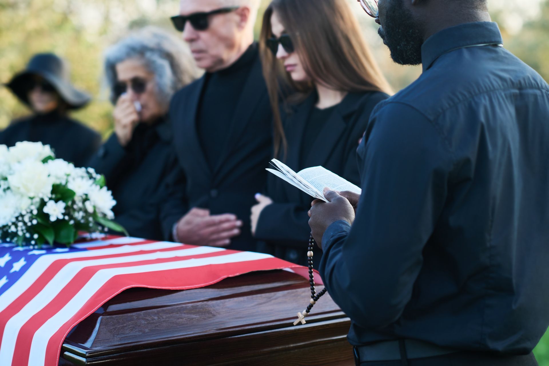 People mourning at a funeral. A casket draped with an American flag.