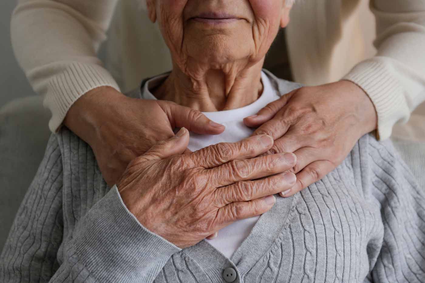 An elderly woman is getting a massage from a caregiver.