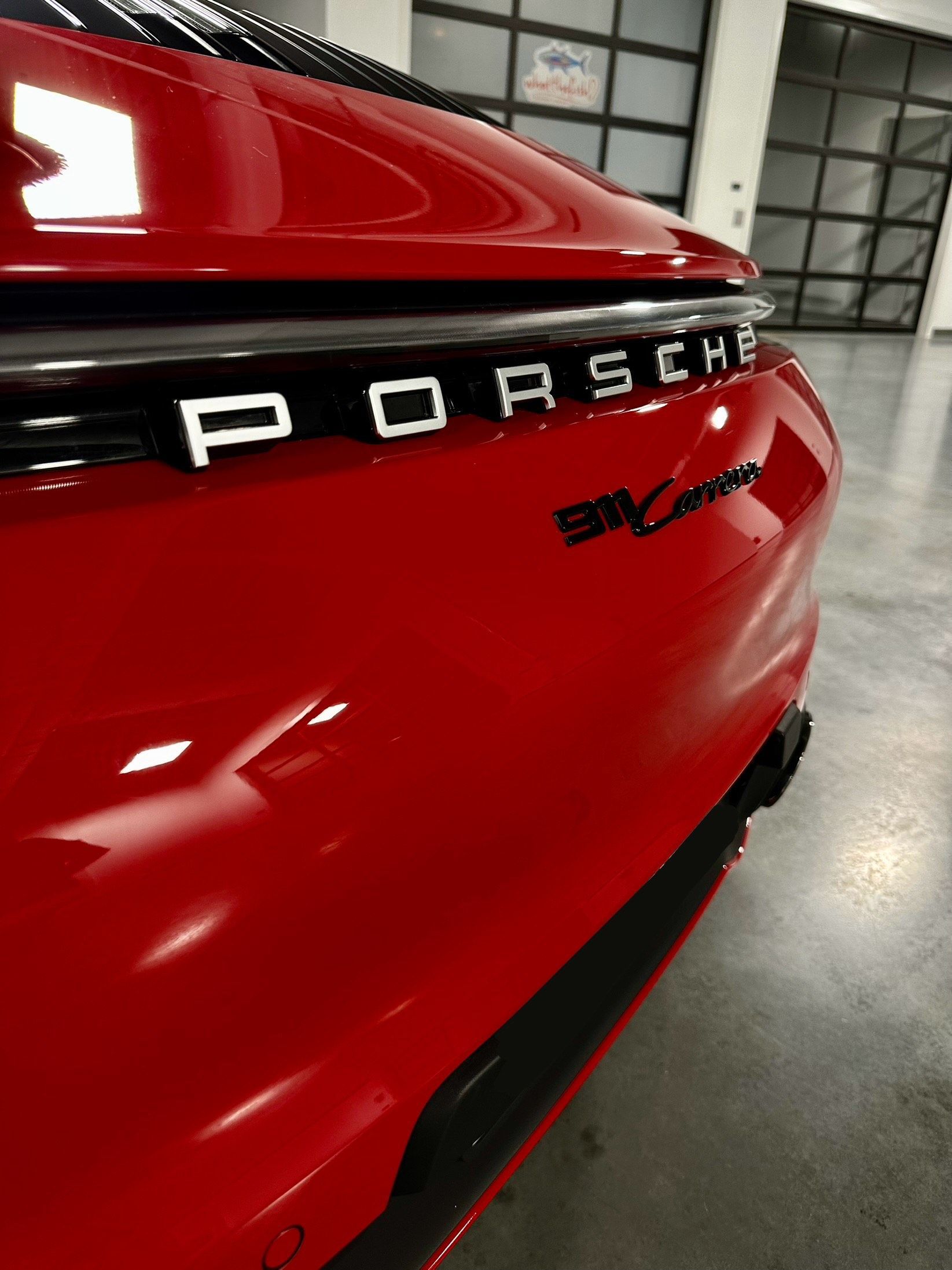 Red Porsche 911 Carrera rear detail with black trim and silver lettering in an indoor setting.