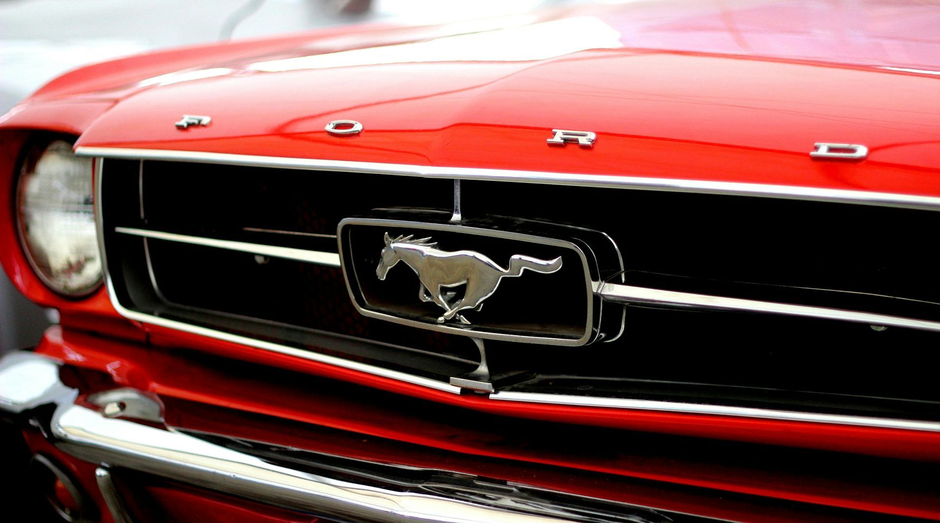 A red ford mustang with a horse on the grille