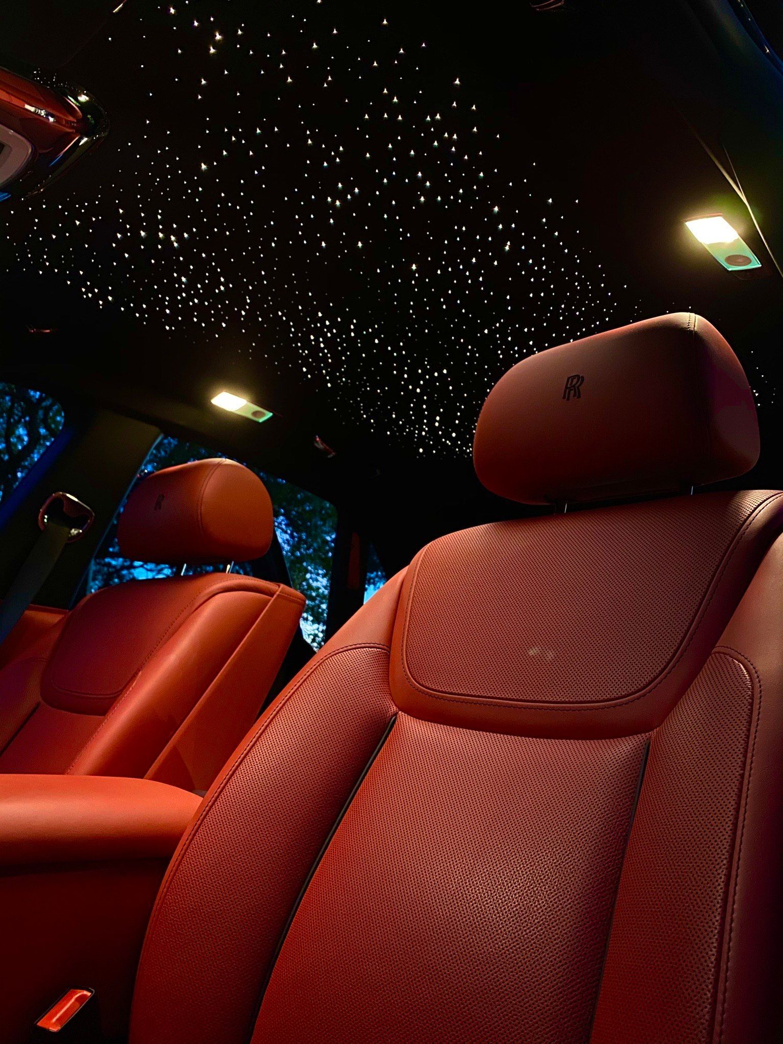 Red leather car seats under a black ceiling with star-like lights.