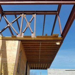 Steel beams and wood framework of a building under construction with a blue sky background.