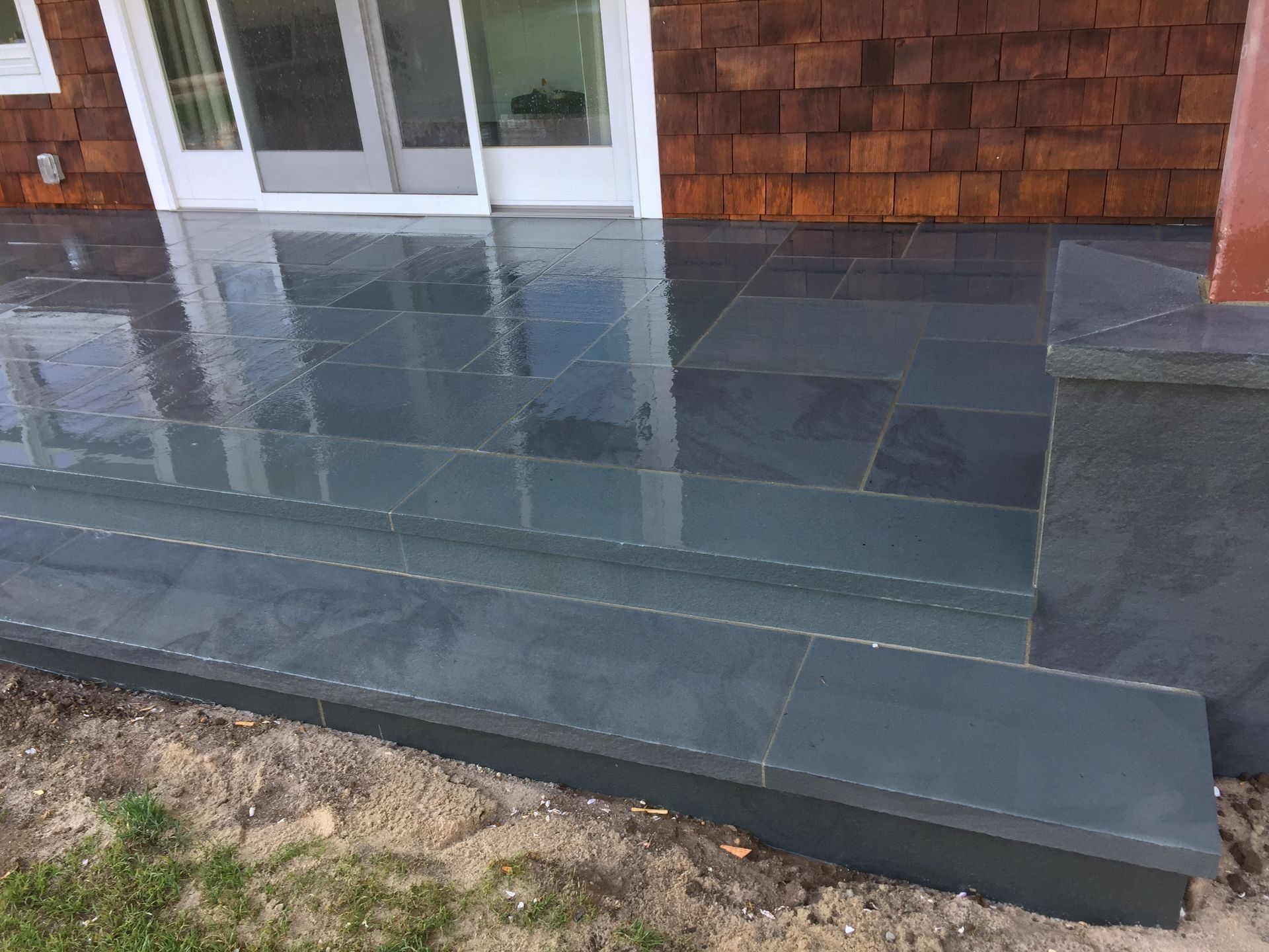 Slate steps leading to a house with a wet, dark stone patio.