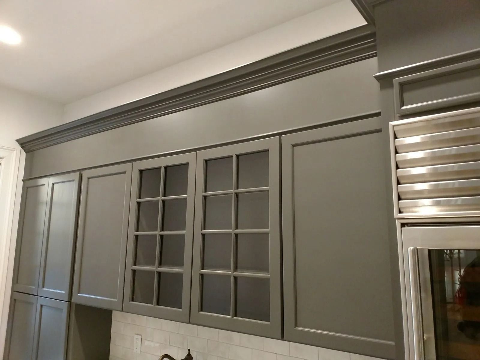 Gray kitchen cabinets with glass-paneled doors and decorative molding.
