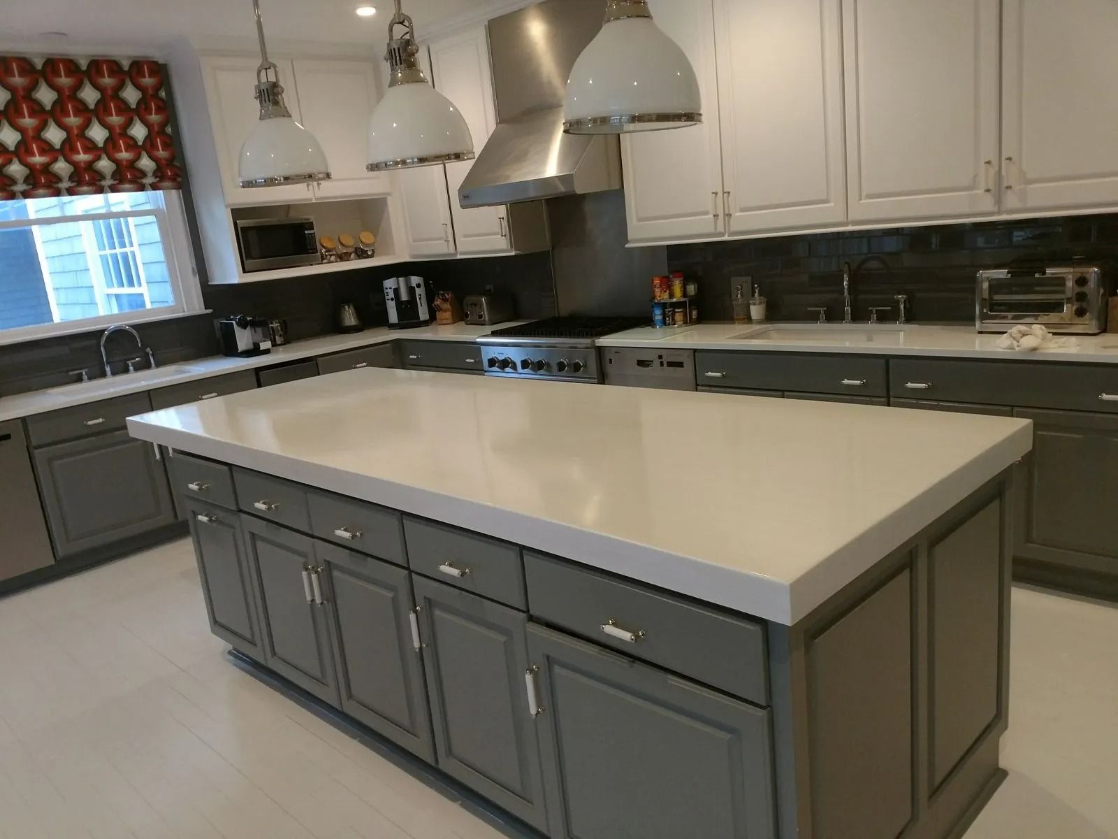 Modern kitchen with gray island, white countertops, gray and white cabinets, and stainless steel appliances.