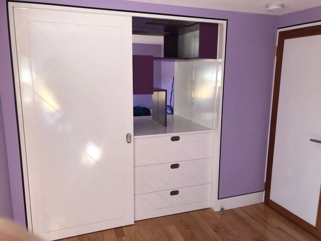 White closet with sliding door, purple accents, and a wooden door on the right.