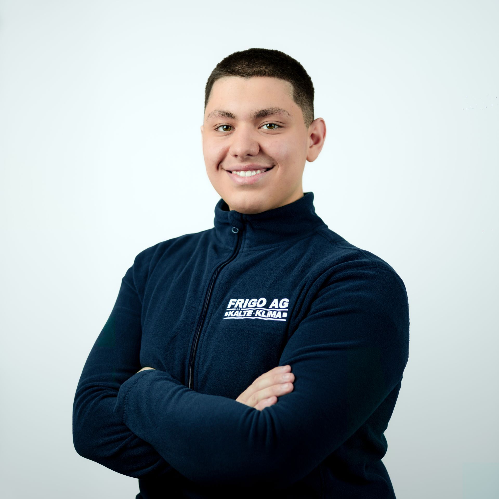 Mann in blauer Fleecejacke mit verschränkten Armen, lächelnd. Das Logo „FRIGO AG“ ist sichtbar.