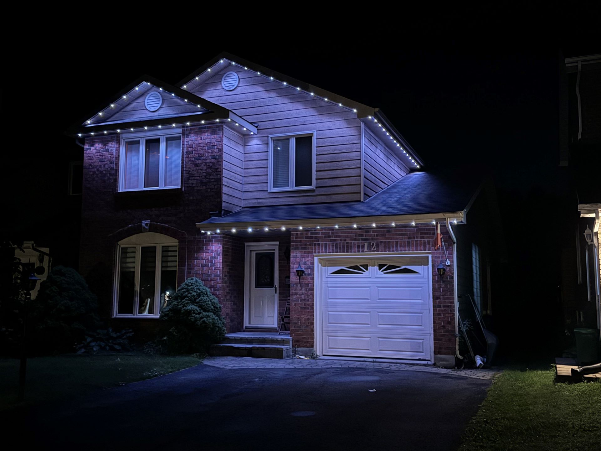 A house with christmas lights on it is lit up at night.