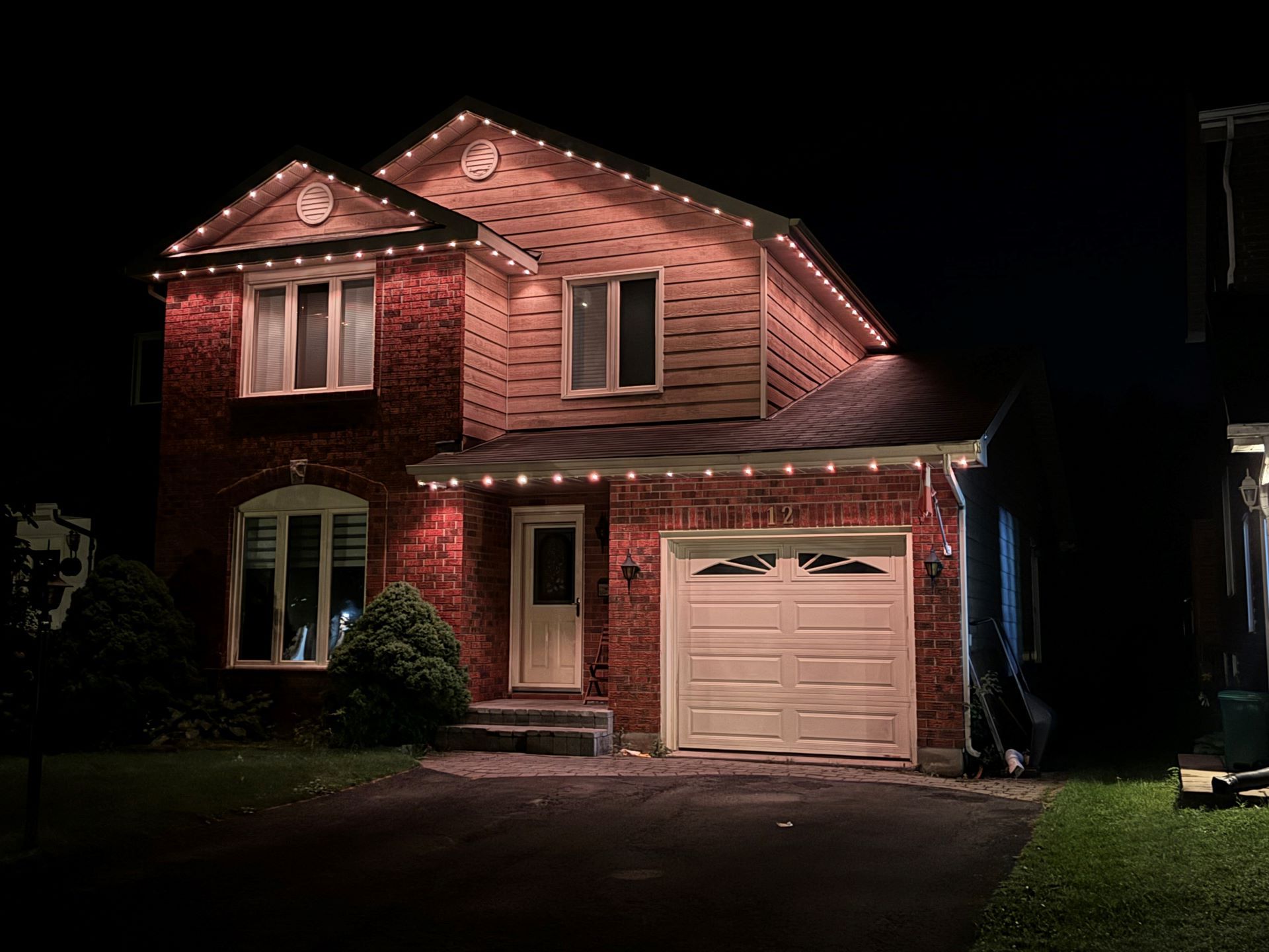 A brick house with christmas lights on it is lit up at night.