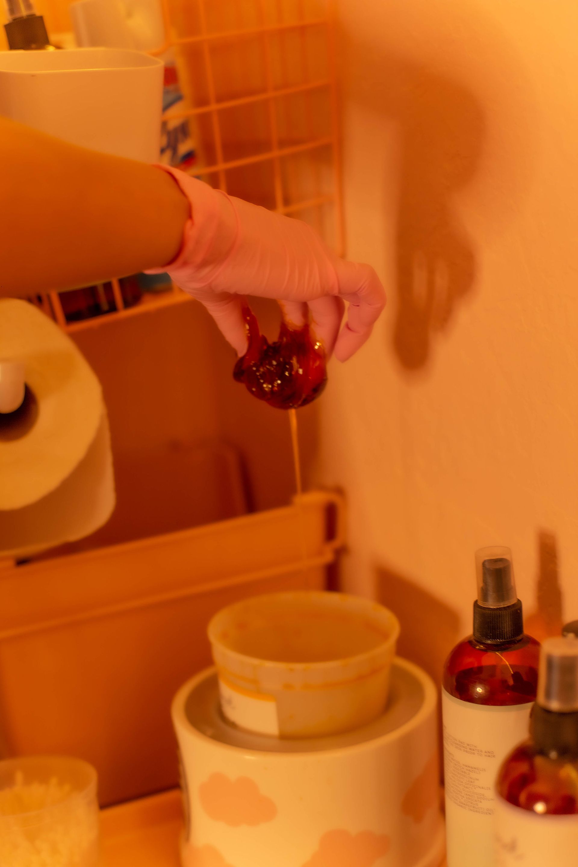Hand holding a small, red, round object. Interior setting with shelves and beauty products.
