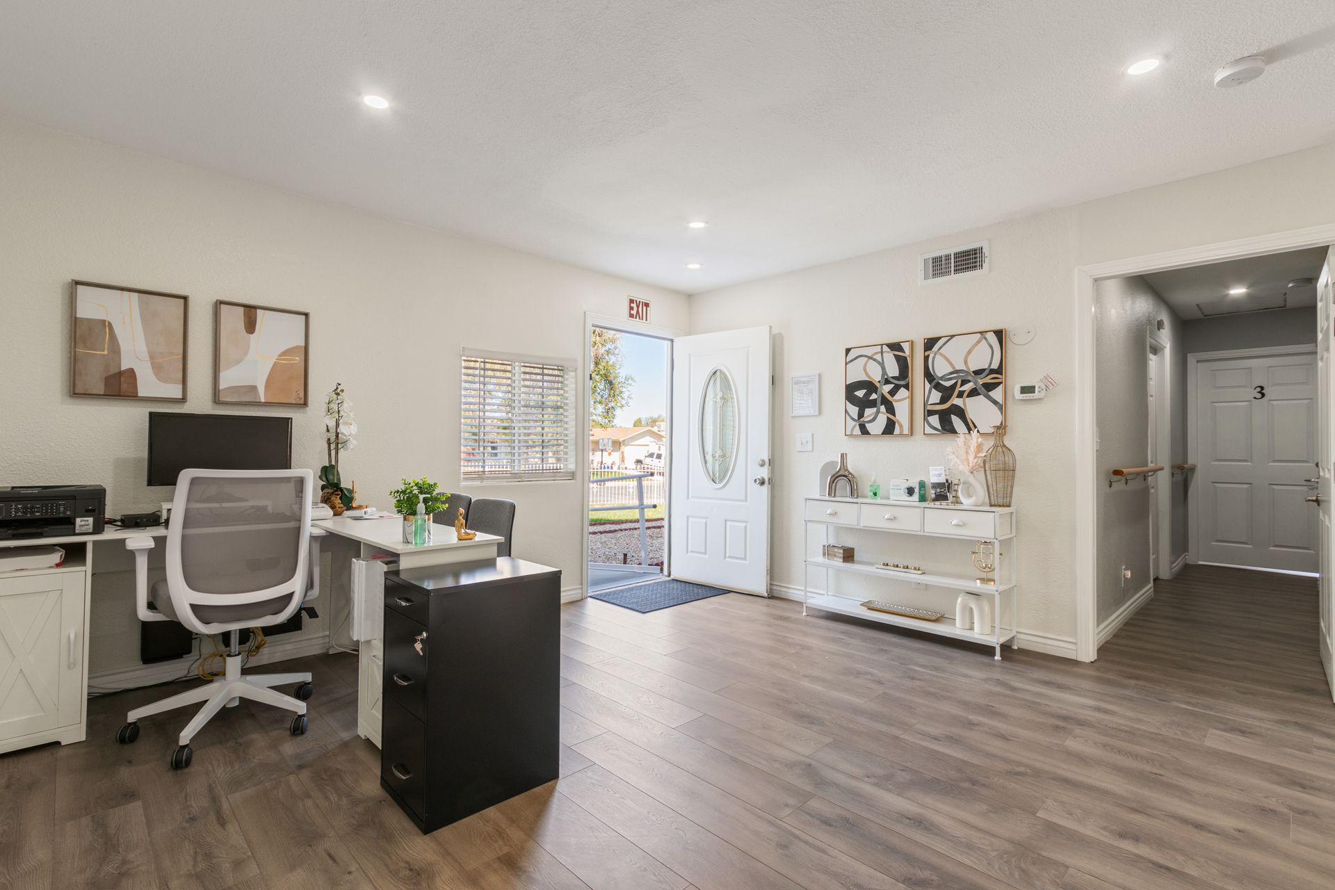Bright office interior with desk, art, and open front door.