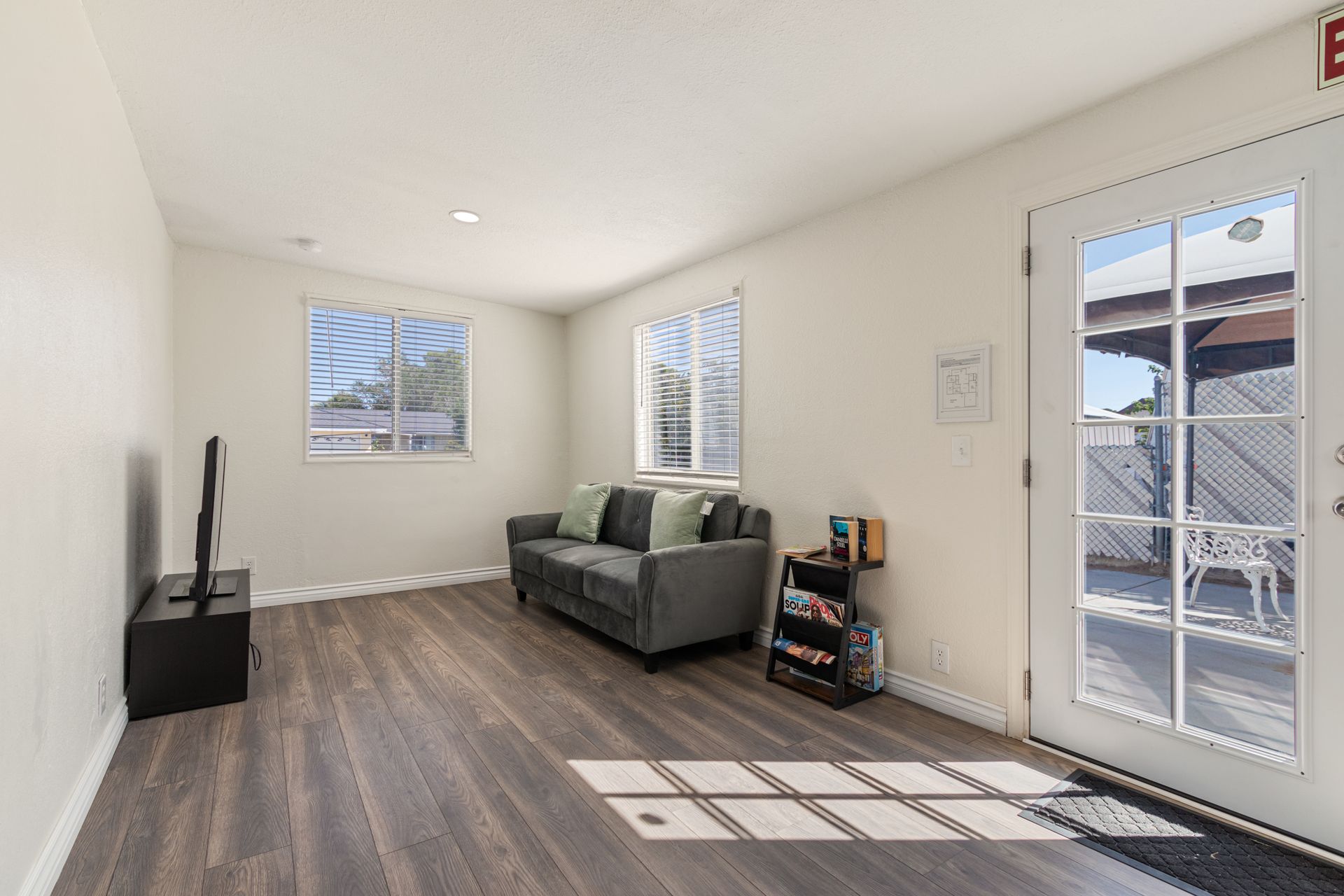 Living room with sofa, TV, windows, and a door leading to an outdoor area.