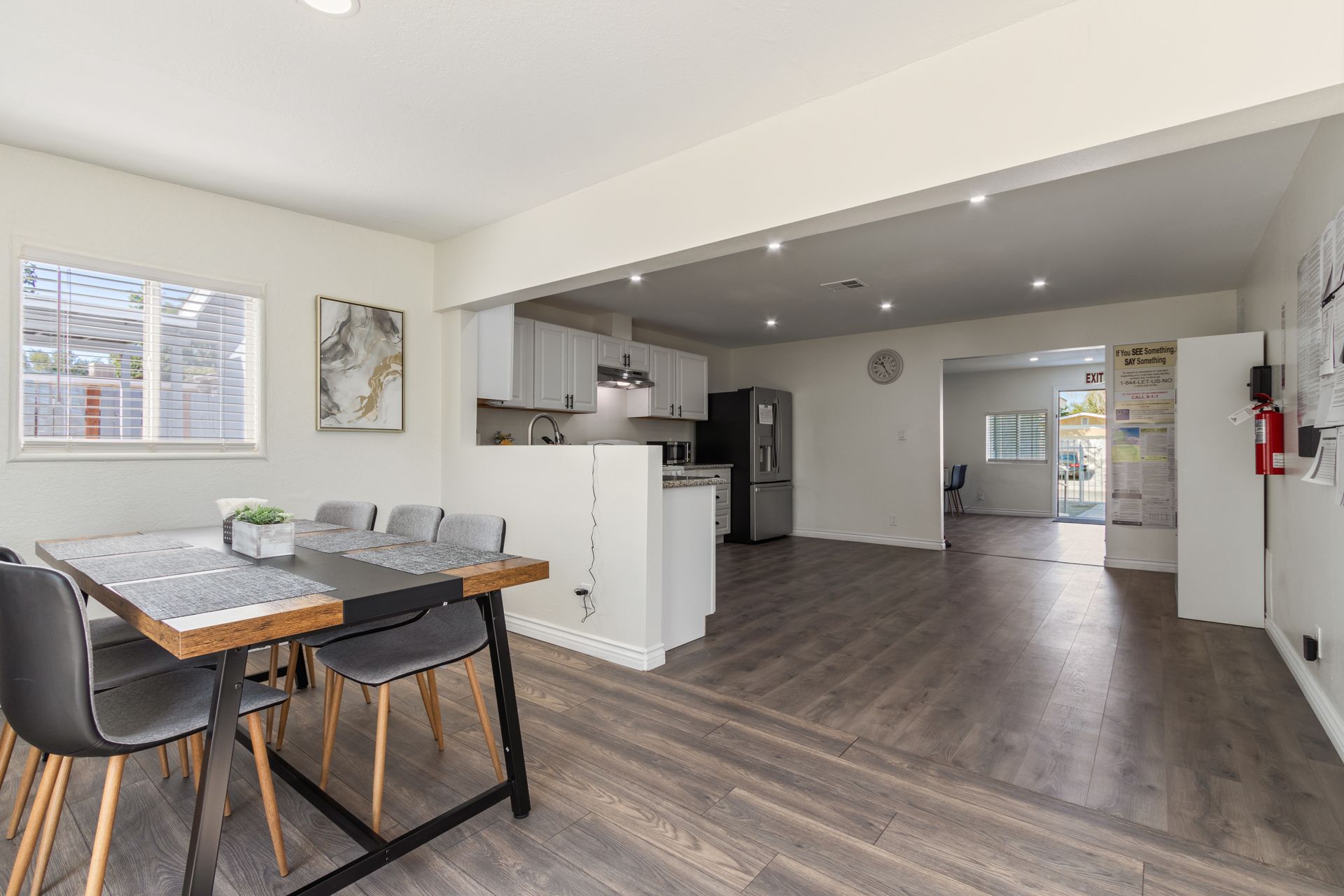 Dining area with a table and chairs, leading to a kitchen and open living space.