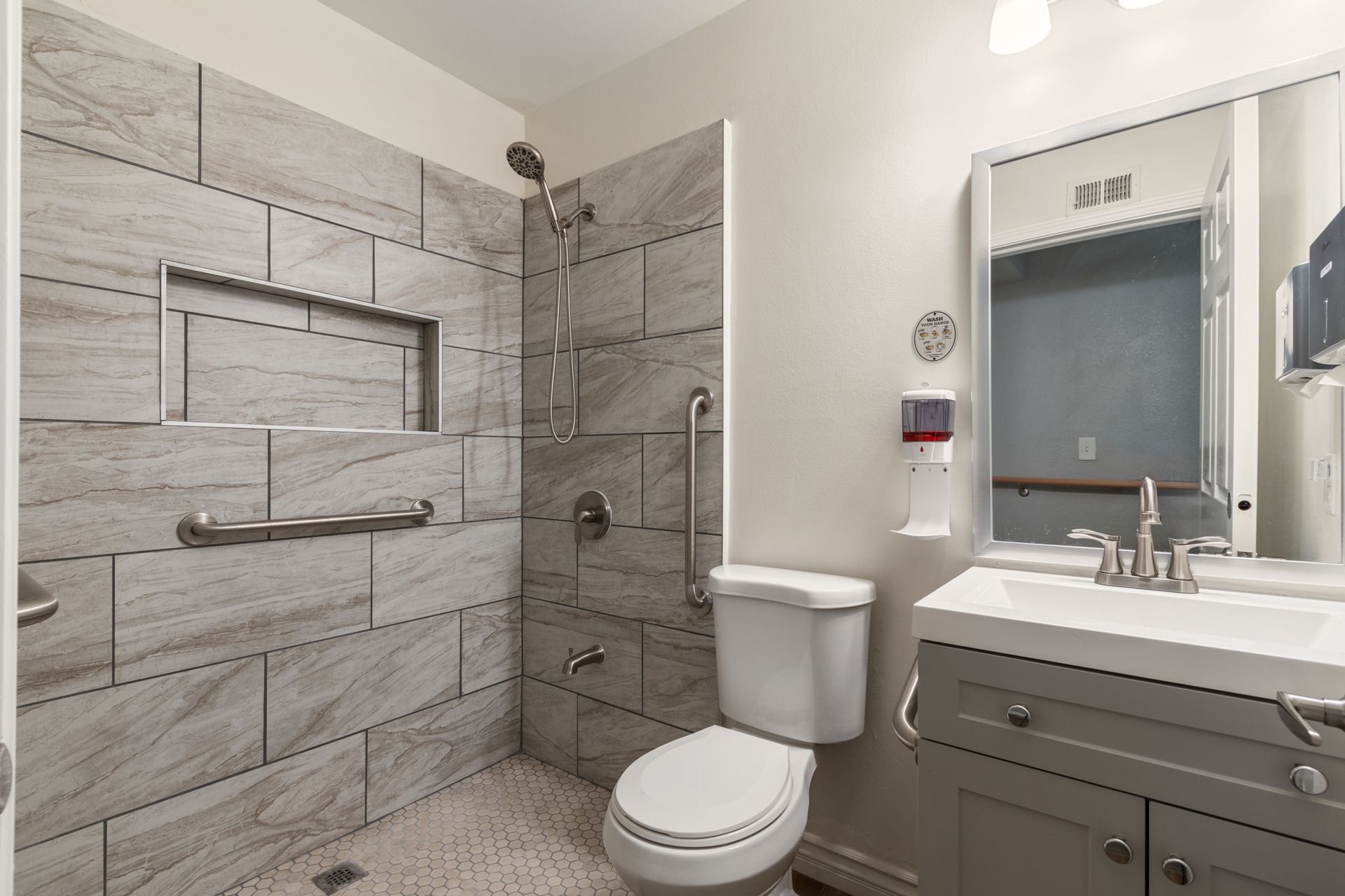 Accessible bathroom with tiled shower, grab bars, and low-mounted sink.