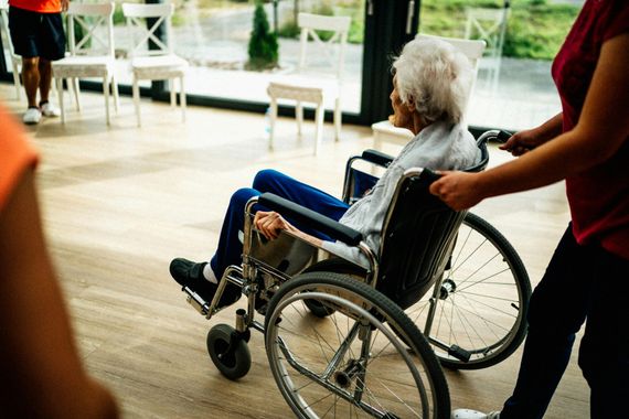 Woman in wheelchair receives pills from man, another woman in kitchen. A Helping Hand Home Care in Lancaster, CA.